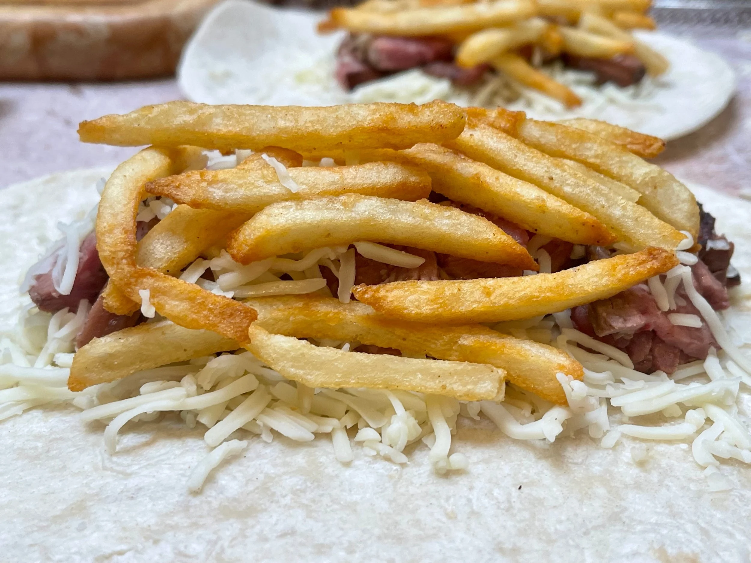 Tortilla piled with cheese, carne asada, and French fries