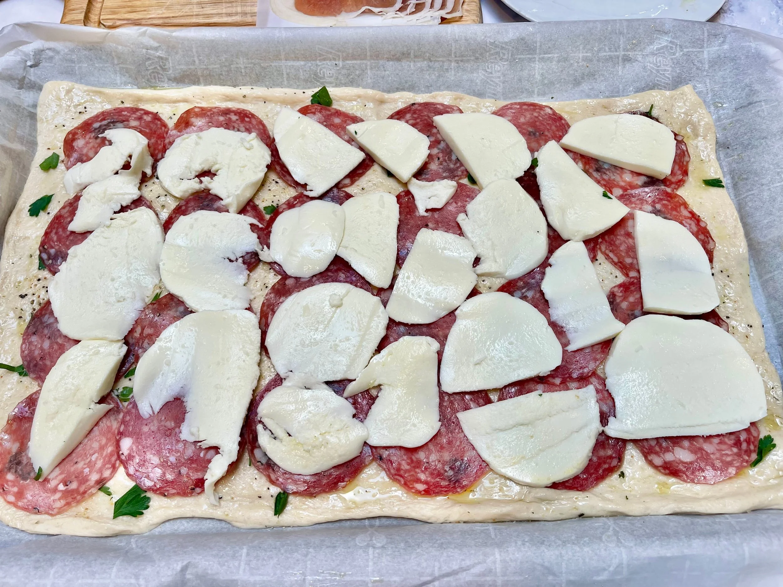 Sliced mozzarella on top of salami