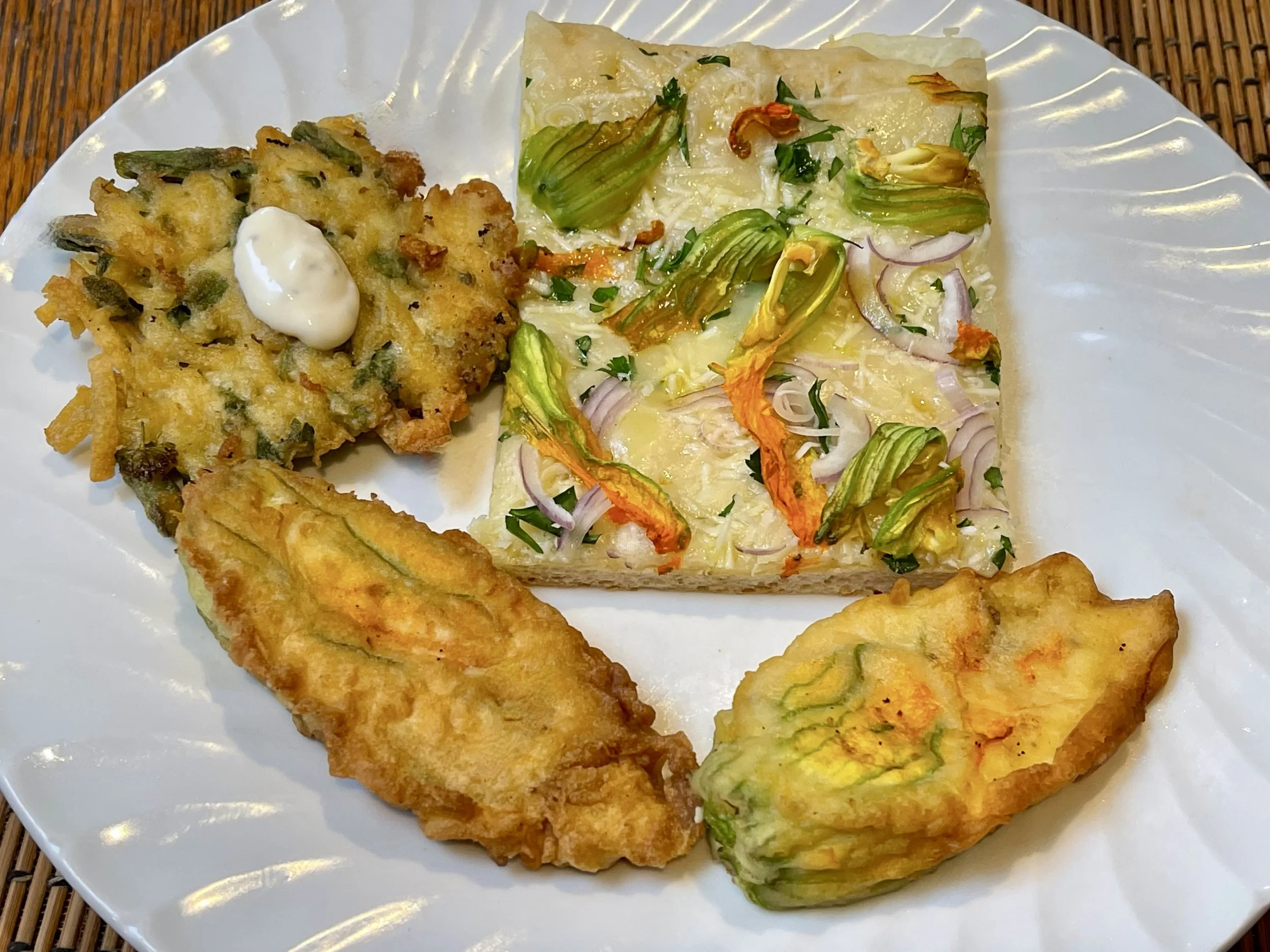Stuffed zucchini blossoms with a zucchini blossom pizza on a plate