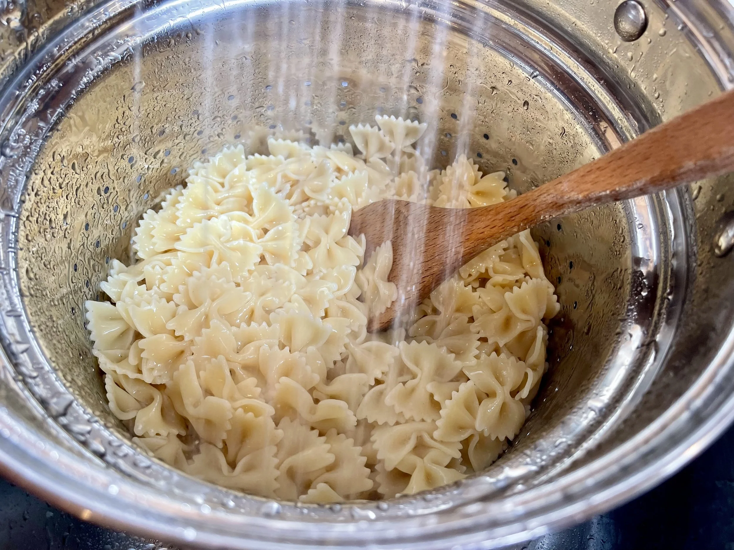 Running cooked pasta under cold water to cool