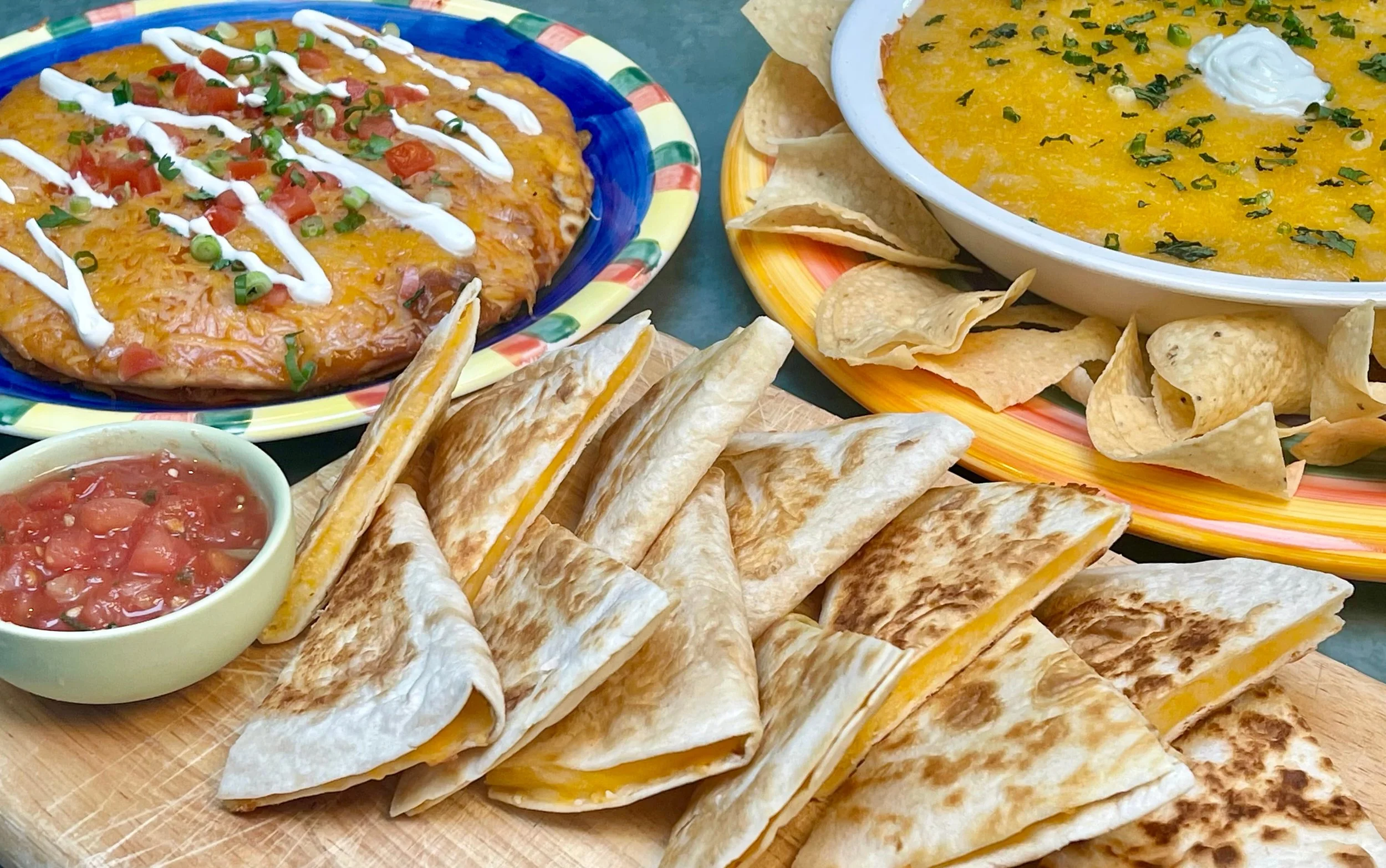 Cheese quesadilla on table with bean dip and Mexican pizza