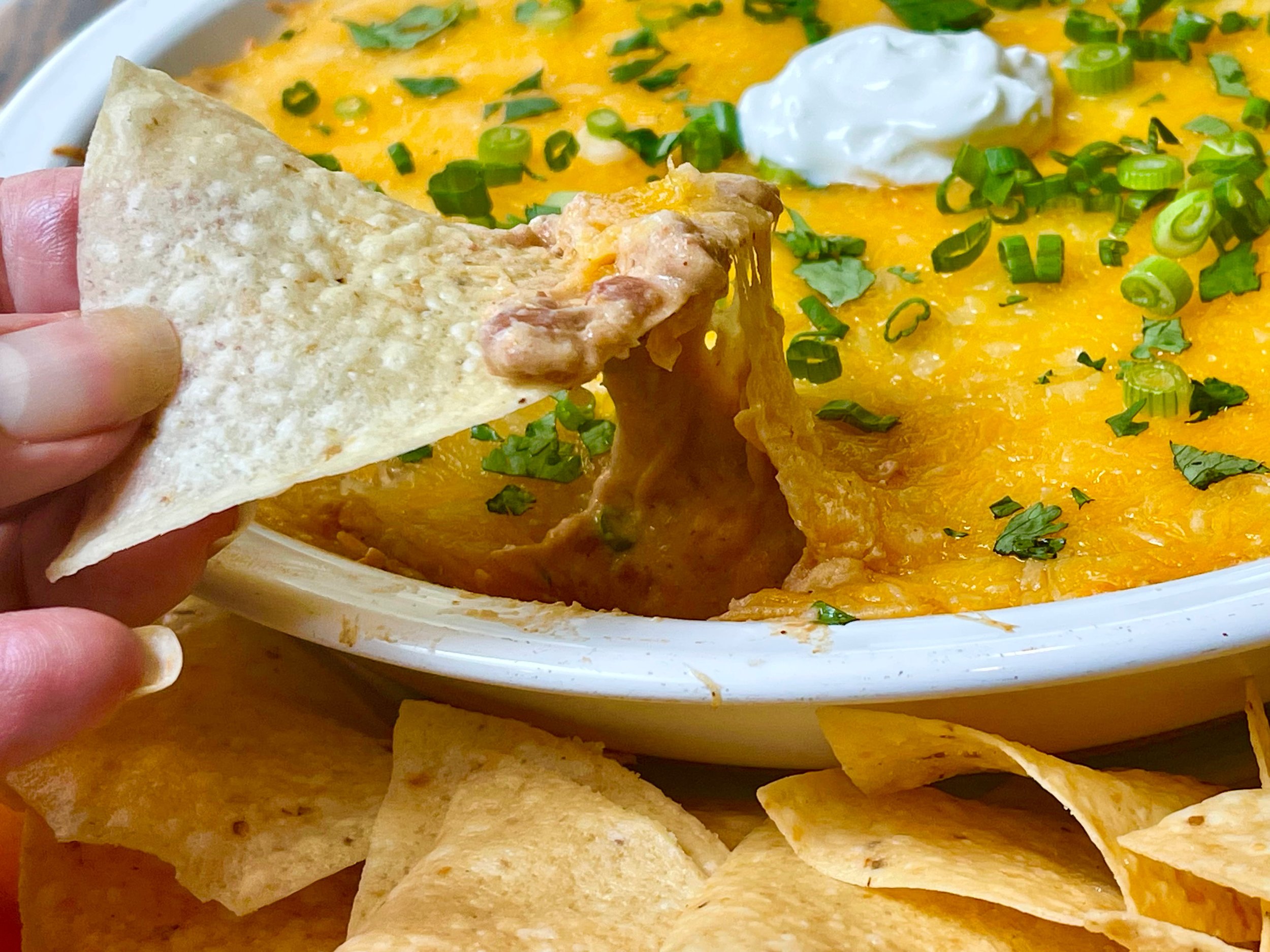 Chip dipped in bean dip with cheese dripping