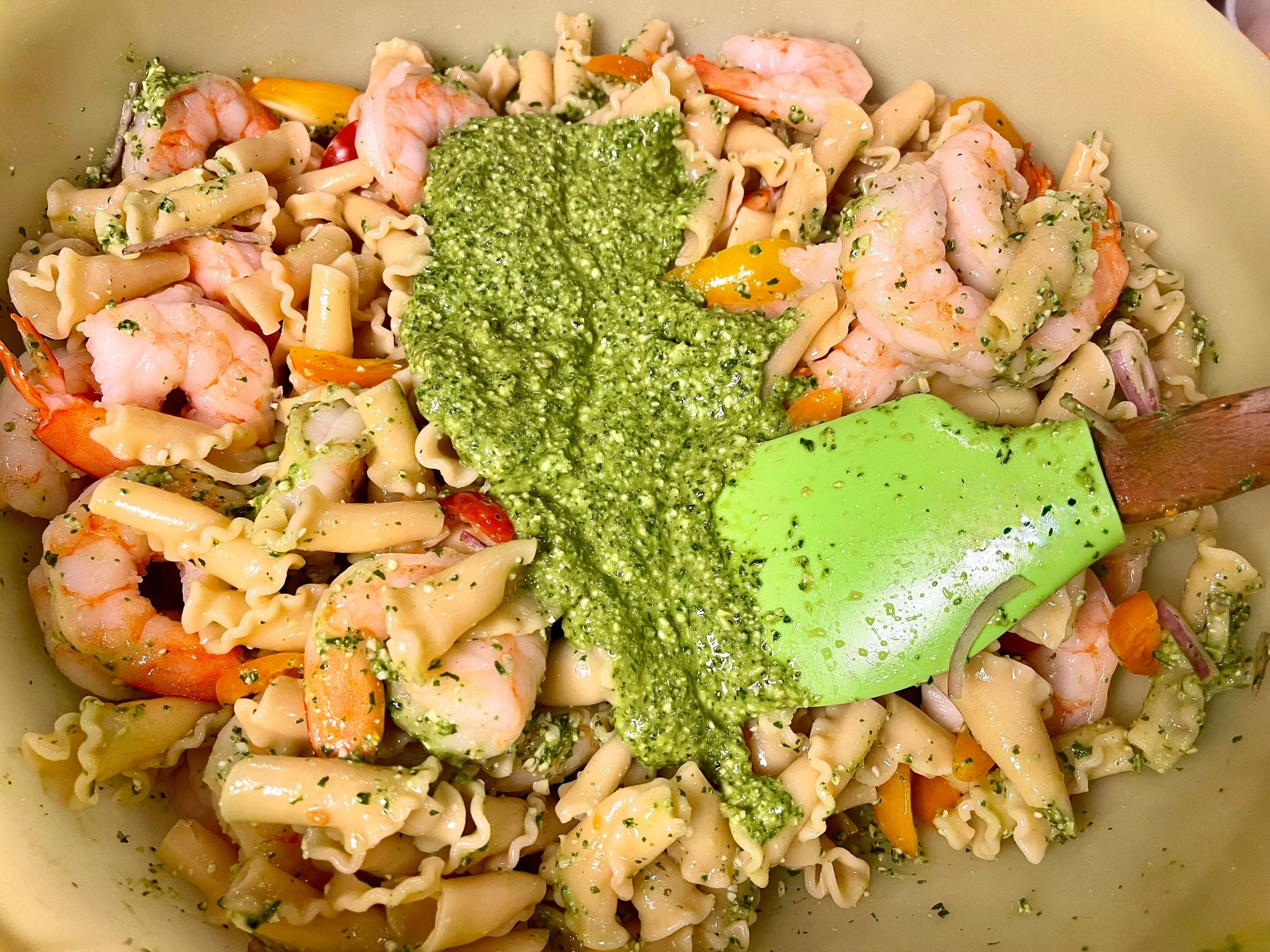 Mixing the pesto into the shrimp pasta salad
