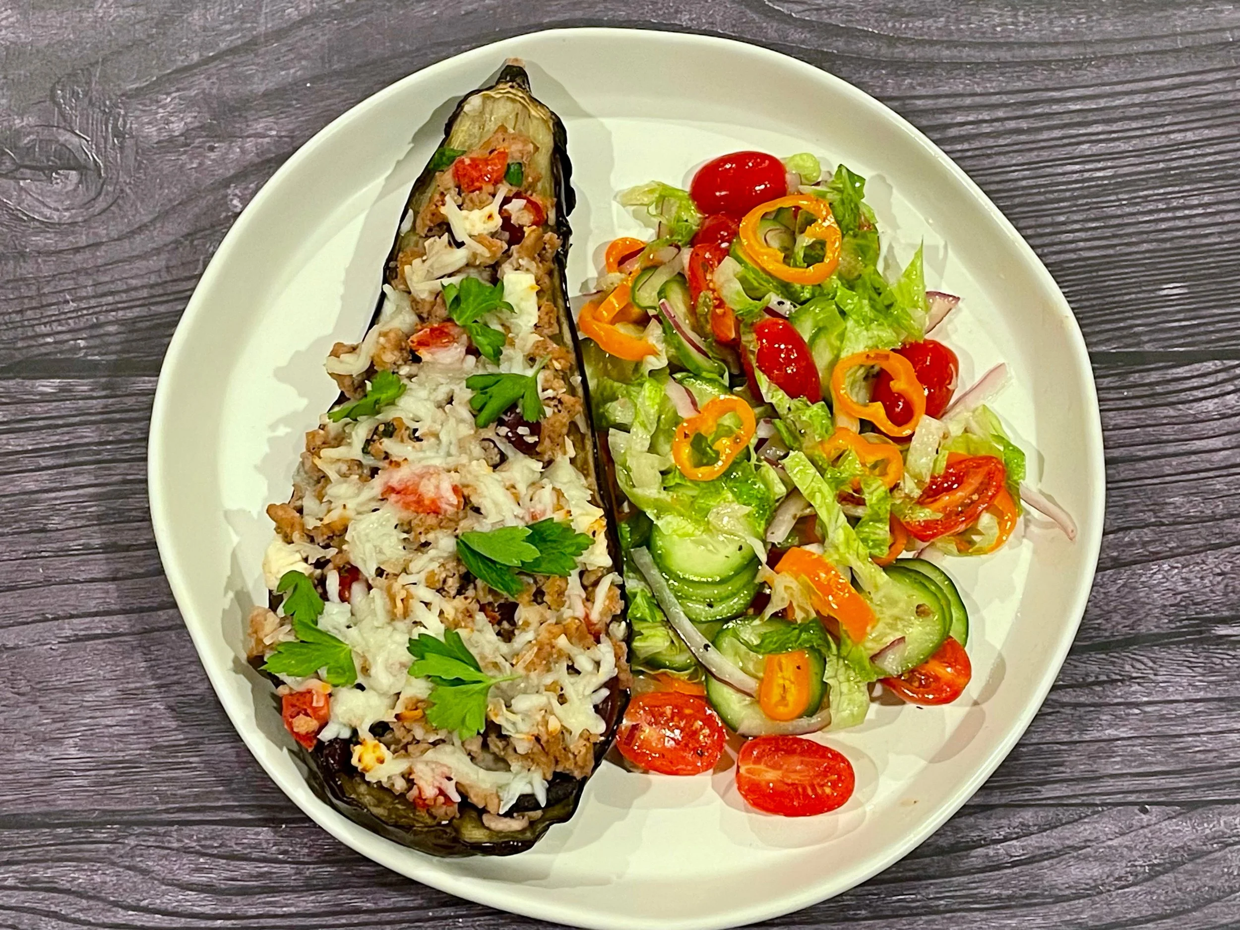 Stuffed eggplant next to side salad
