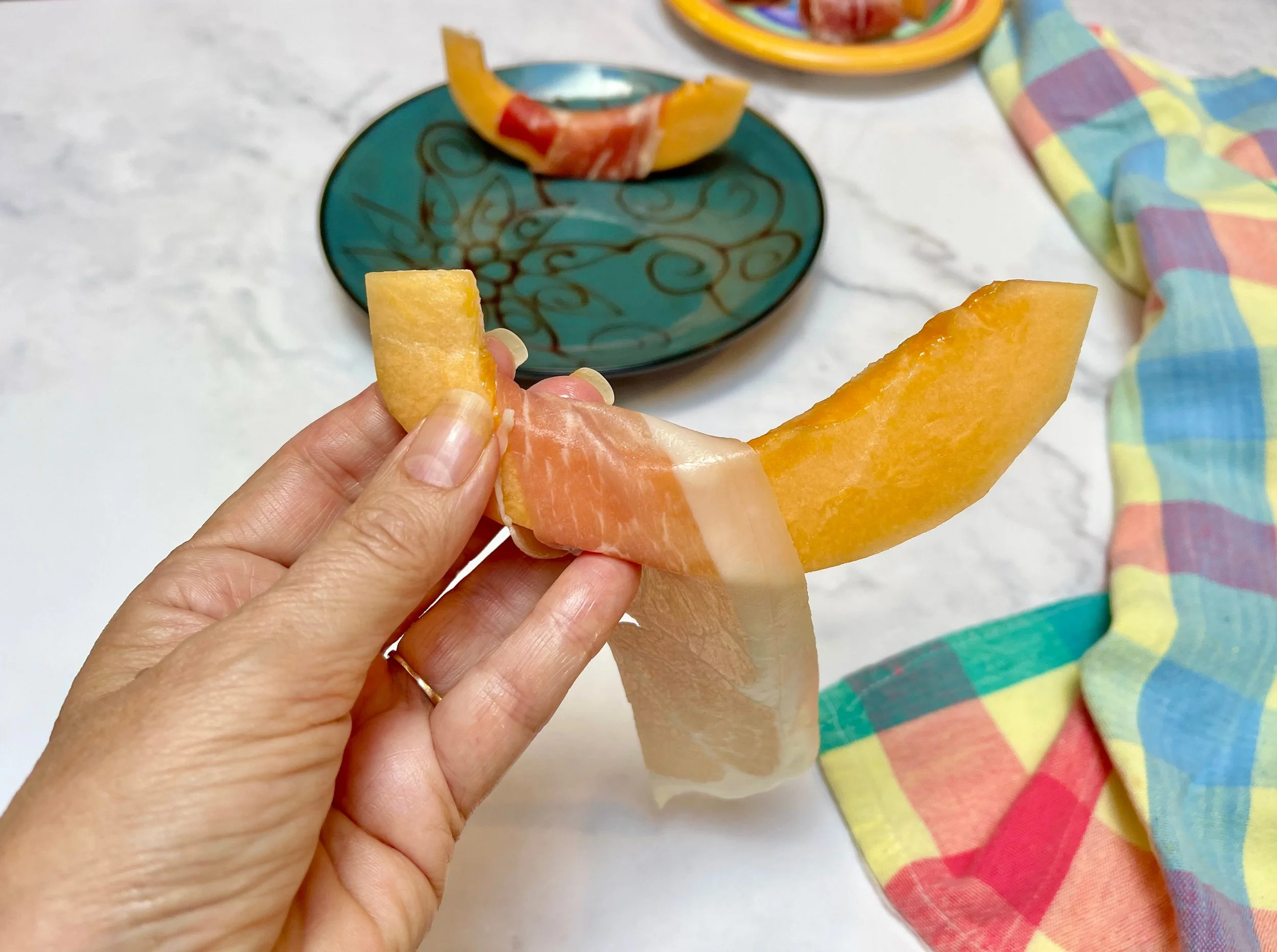 Wrapping the melon wedges in prosciutto
