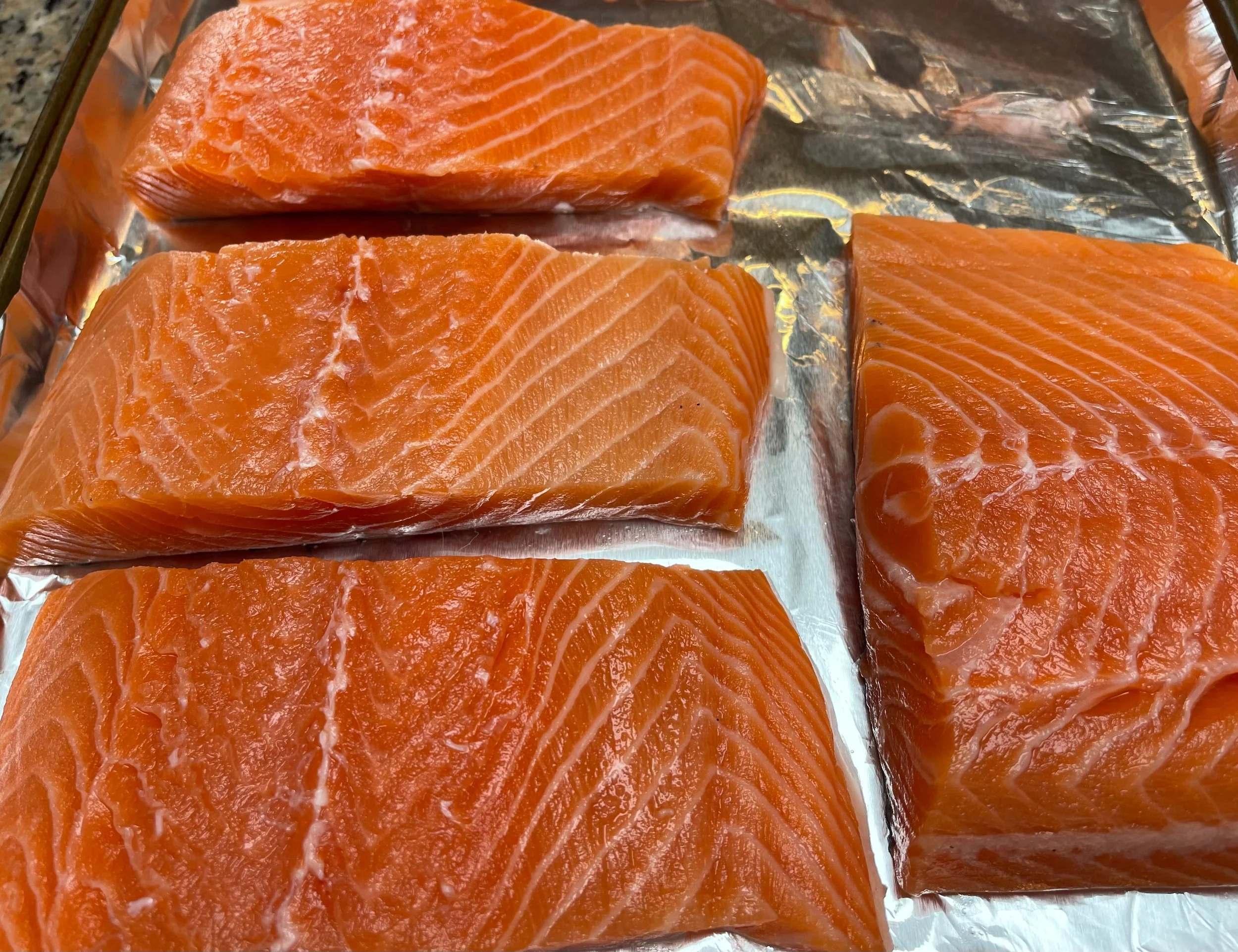 Salmon portioned and placed on sheet pan
