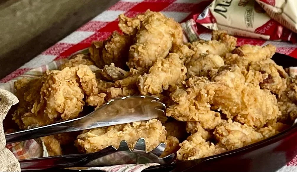 A tray of fried chicken on a picnic table
