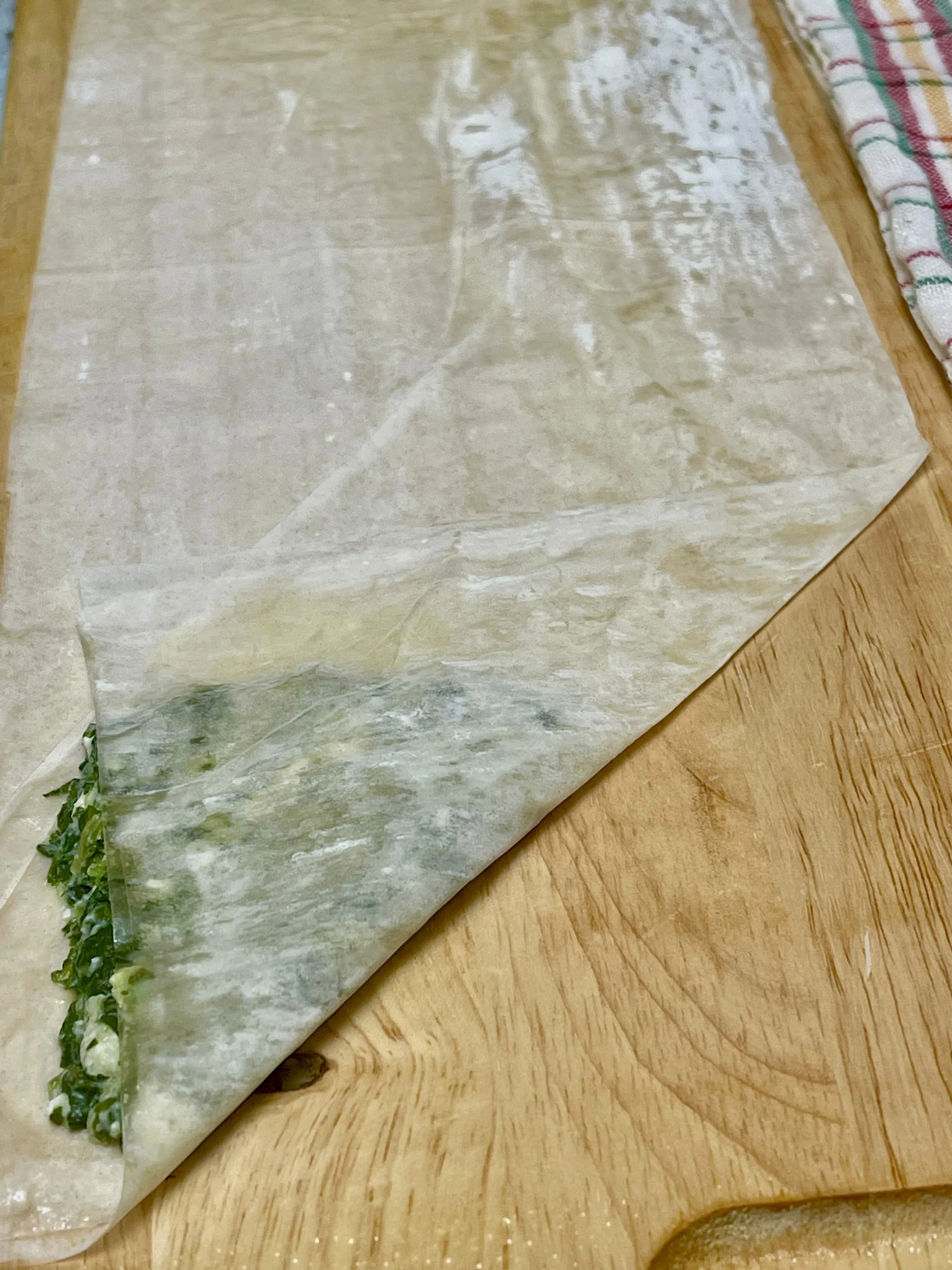 first fold of phyllo dough with spinach in the corner