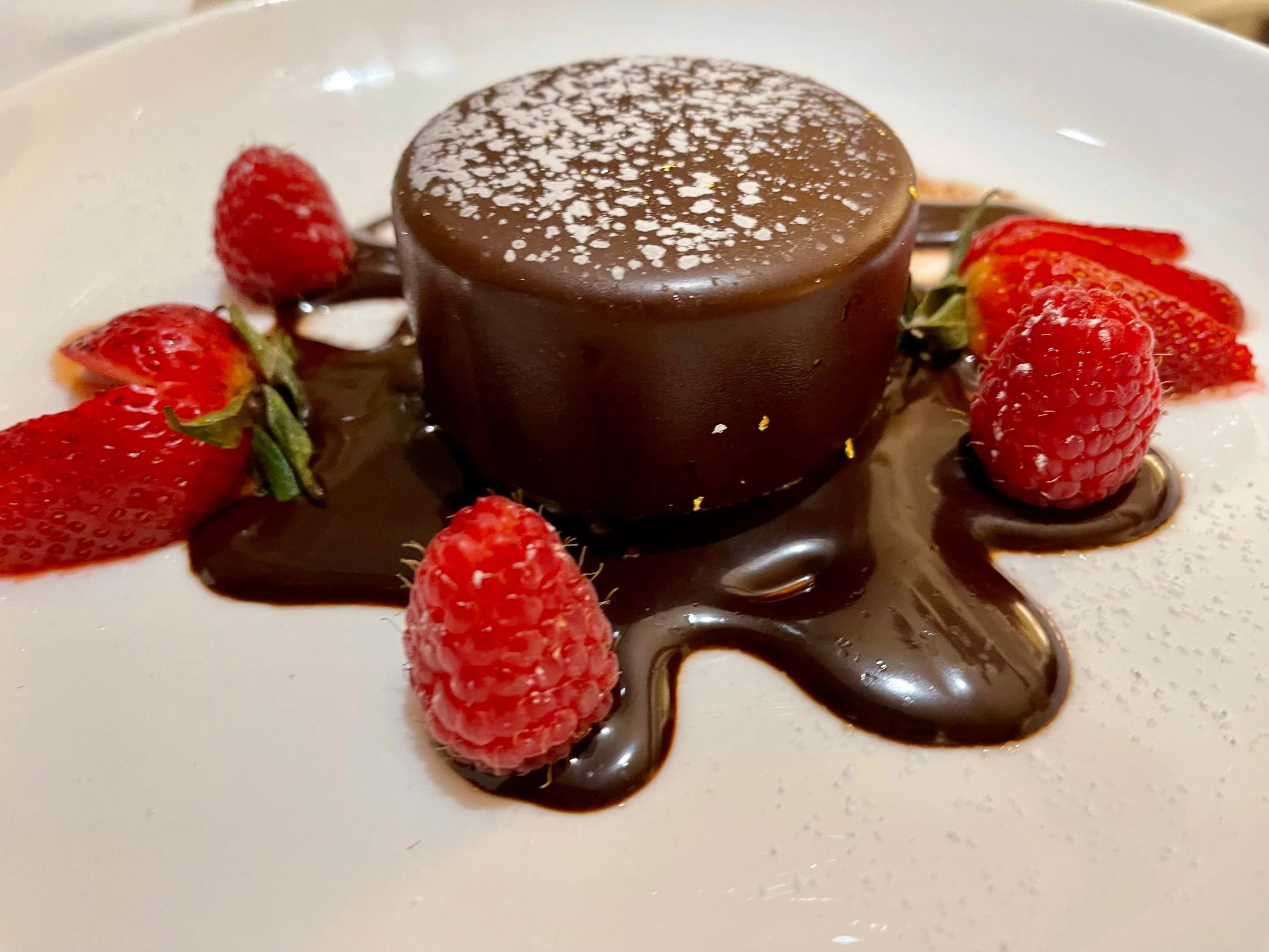 A chocolate covered dessert with berries in the syrup