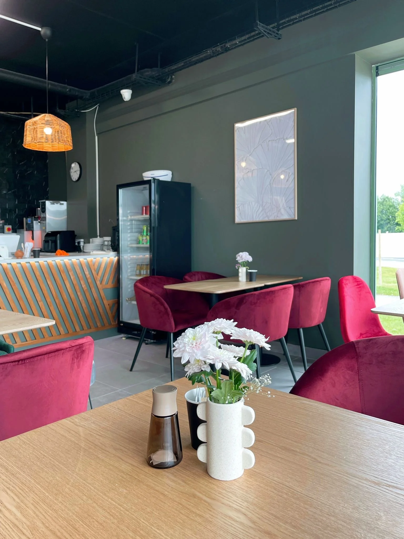 Warm hospitality interior with deep pink seating, pendant lighting, and a playful mix of textures and colour.