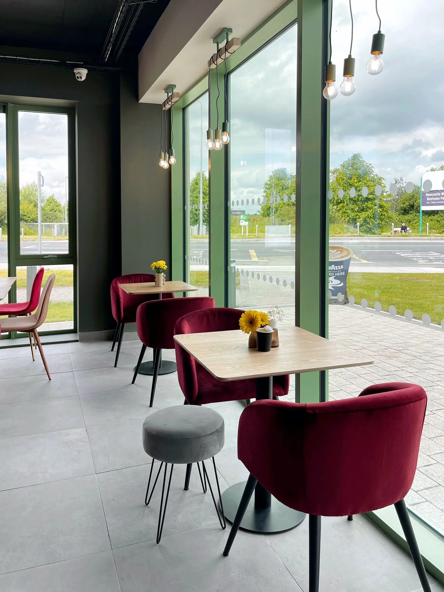 Window-side seating area with berry-toned chairs, green-framed glazing, and natural light throughout.