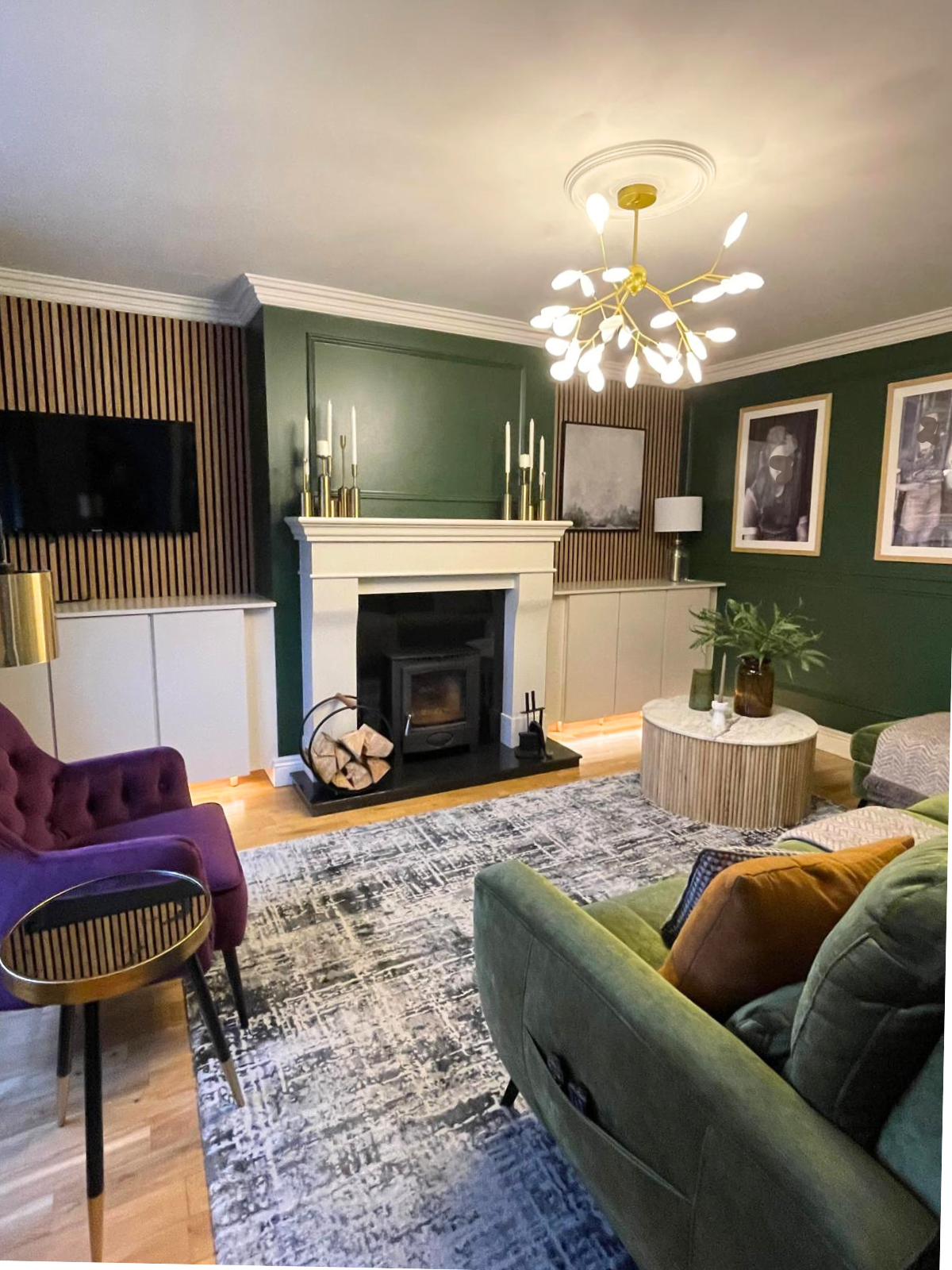 Full room view showing the fireplace, layered seating, statement lighting, and a more cohesive layout throughout the space.