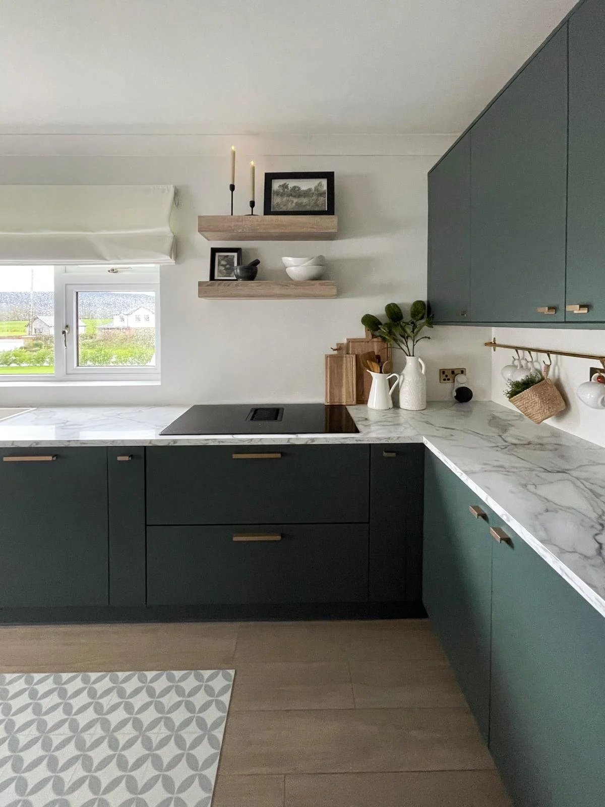 Kitchen corner with muted cabinetry, marble-effect worktops, and a bright window-side workspace.
