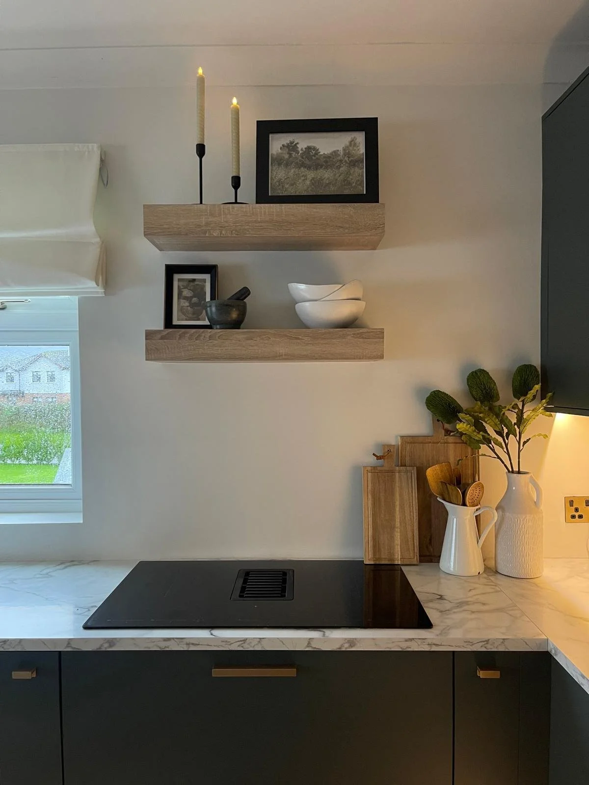 Kitchen corner with muted cabinetry, floating shelves, and a clean, bright finish that feels both practical and polished.