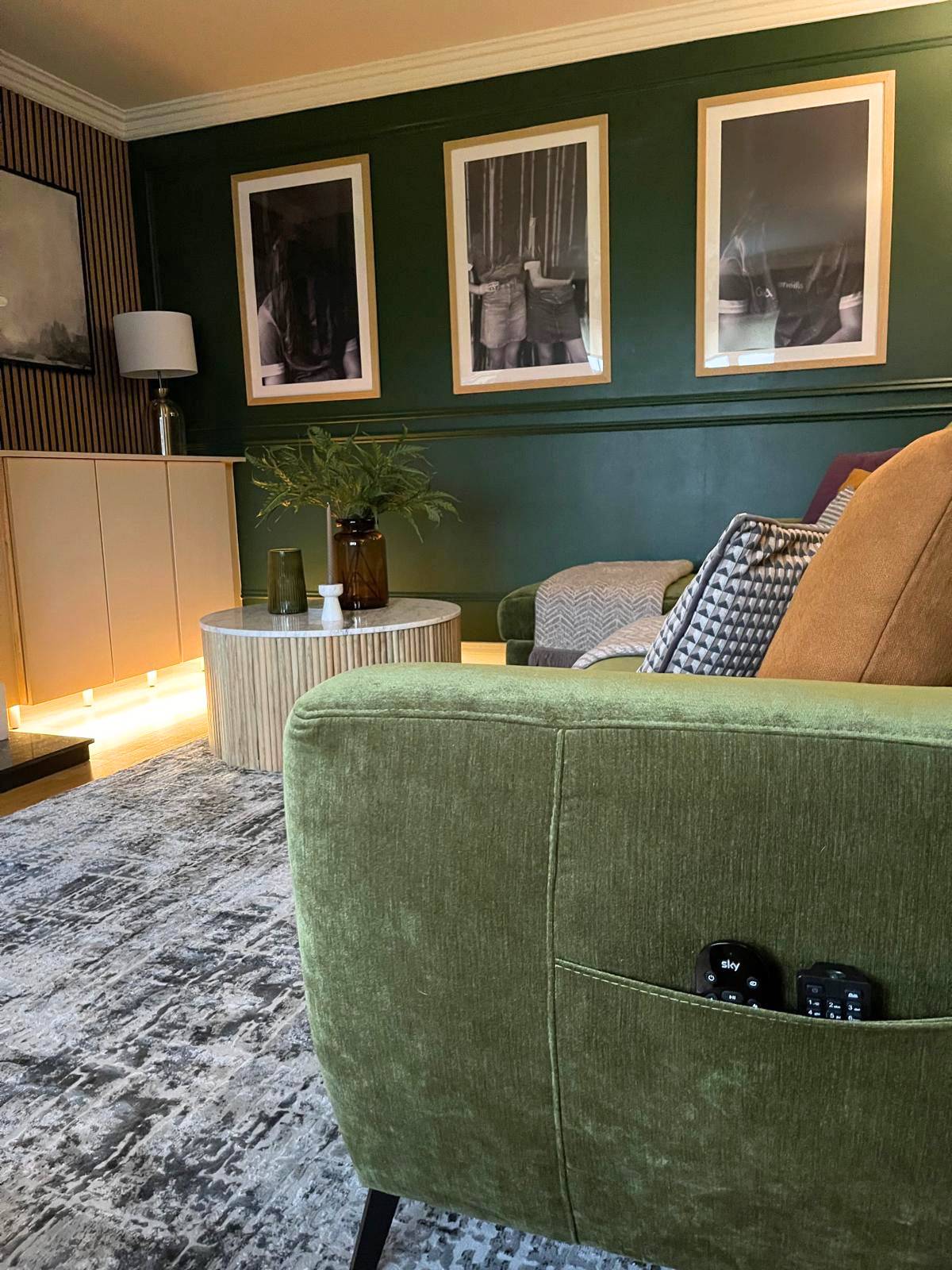 Living room corner with framed artwork, layered textiles, and rich upholstery for a warmer, more enveloping feel.