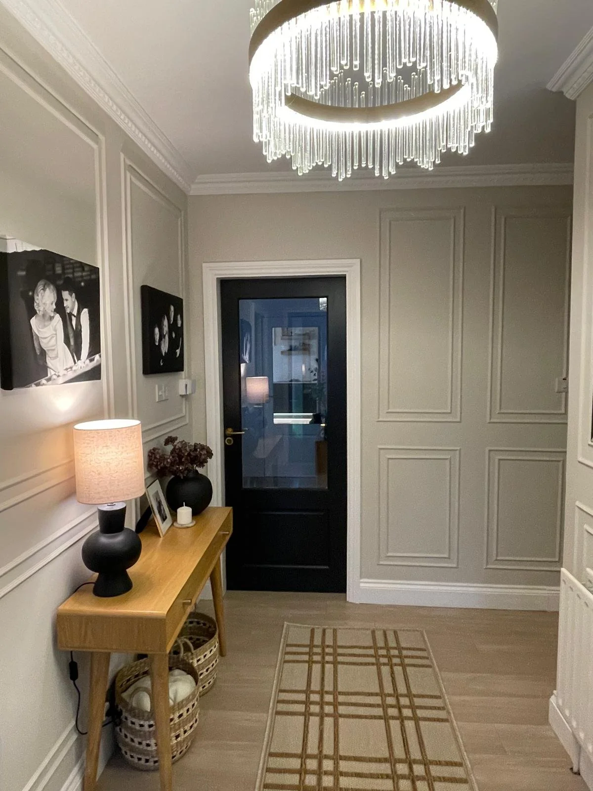 Elegant entry hall with classic wall panelling, a black-framed front door, and warm console styling for a more refined first impression.