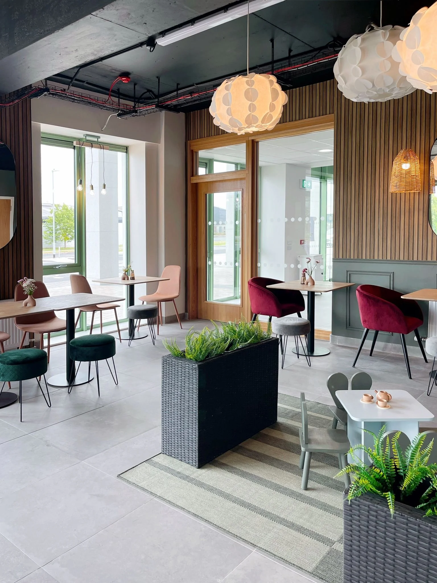 Wide interior view showing layered seating zones, tropical wall finishes, planting, and soft ambient lighting.