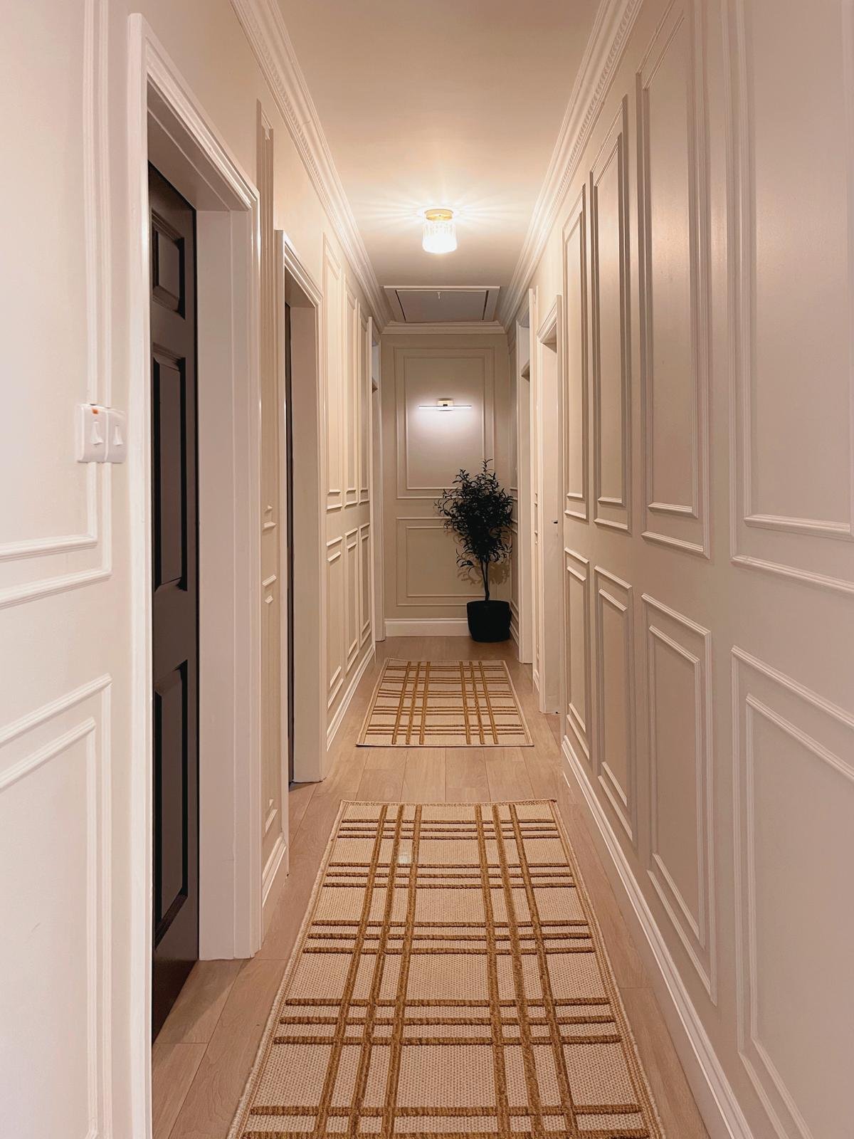 Long hallway with classic wall panelling, warm lighting, and a more elegant, cohesive flow through the home.