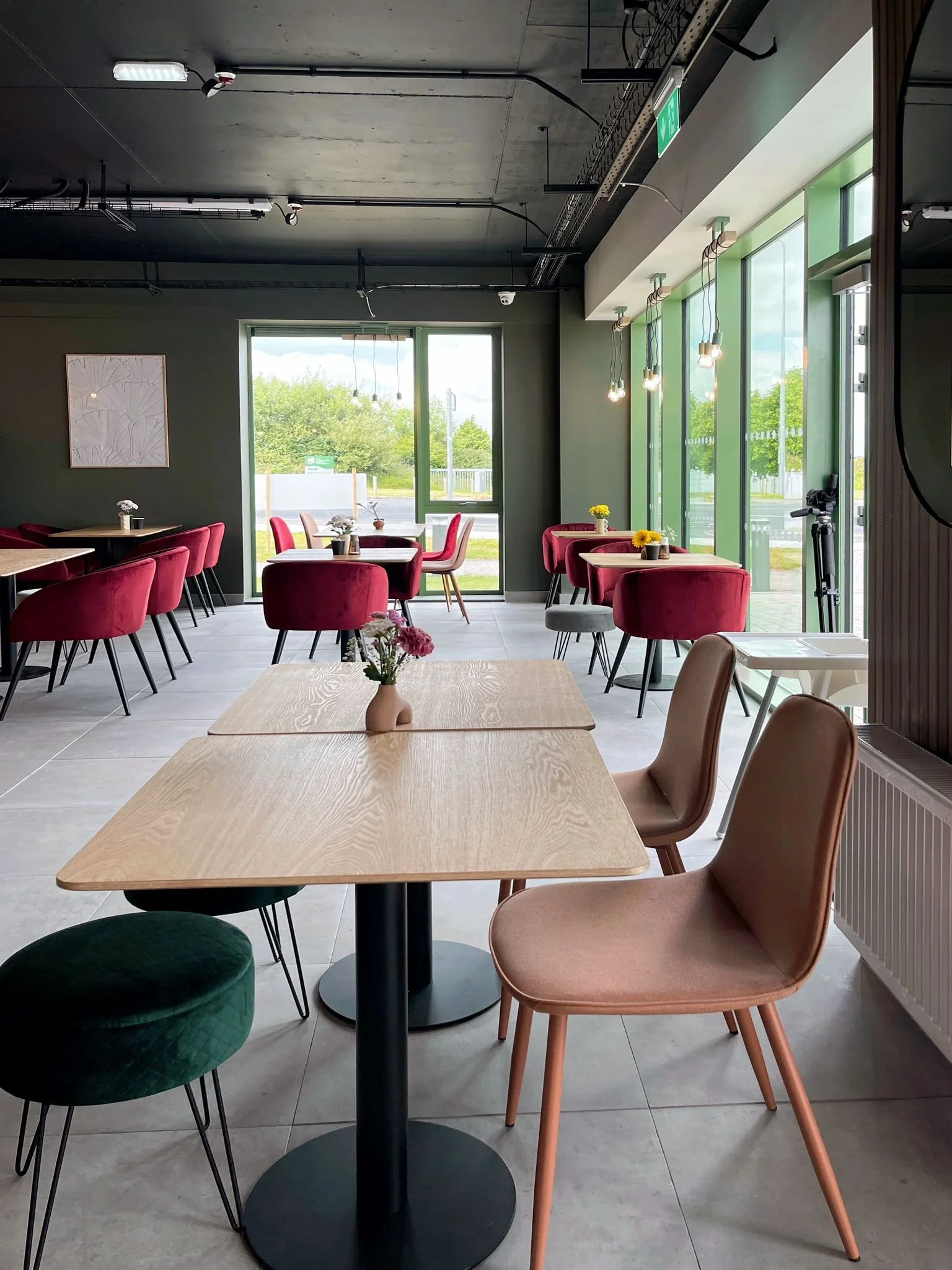 Open-plan dining space with a long table, mixed seating, soft colour accents, and a calm modern layout.