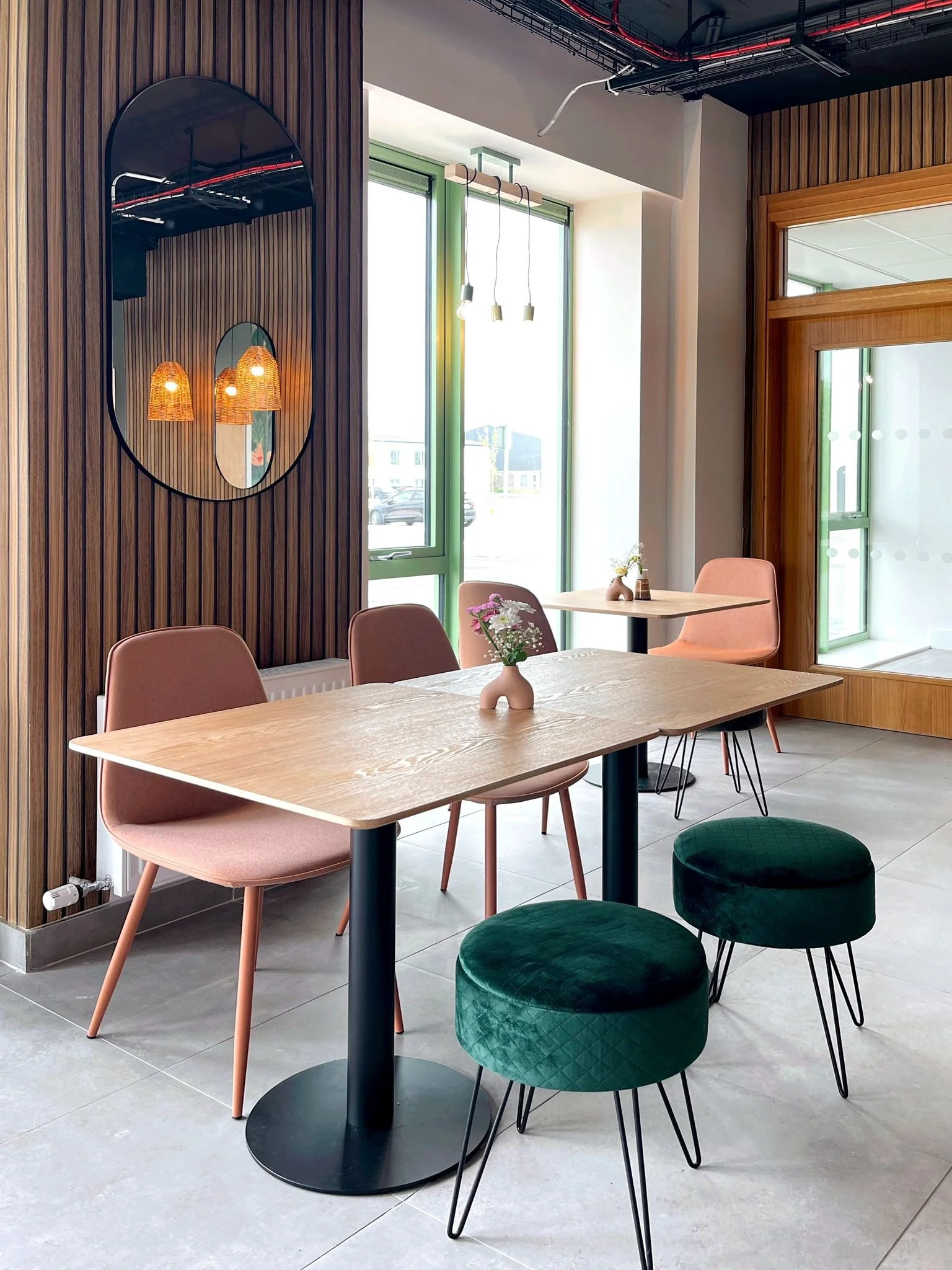 Intimate dining nook with timber slat panelling, blush seating, statement lighting, and mural detail.