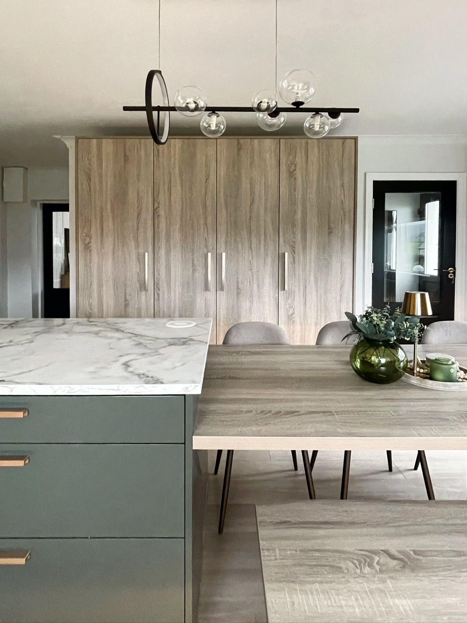 Kitchen detail with woodgrain cabinetry, marble-effect surfaces, and a generous island for daily use.