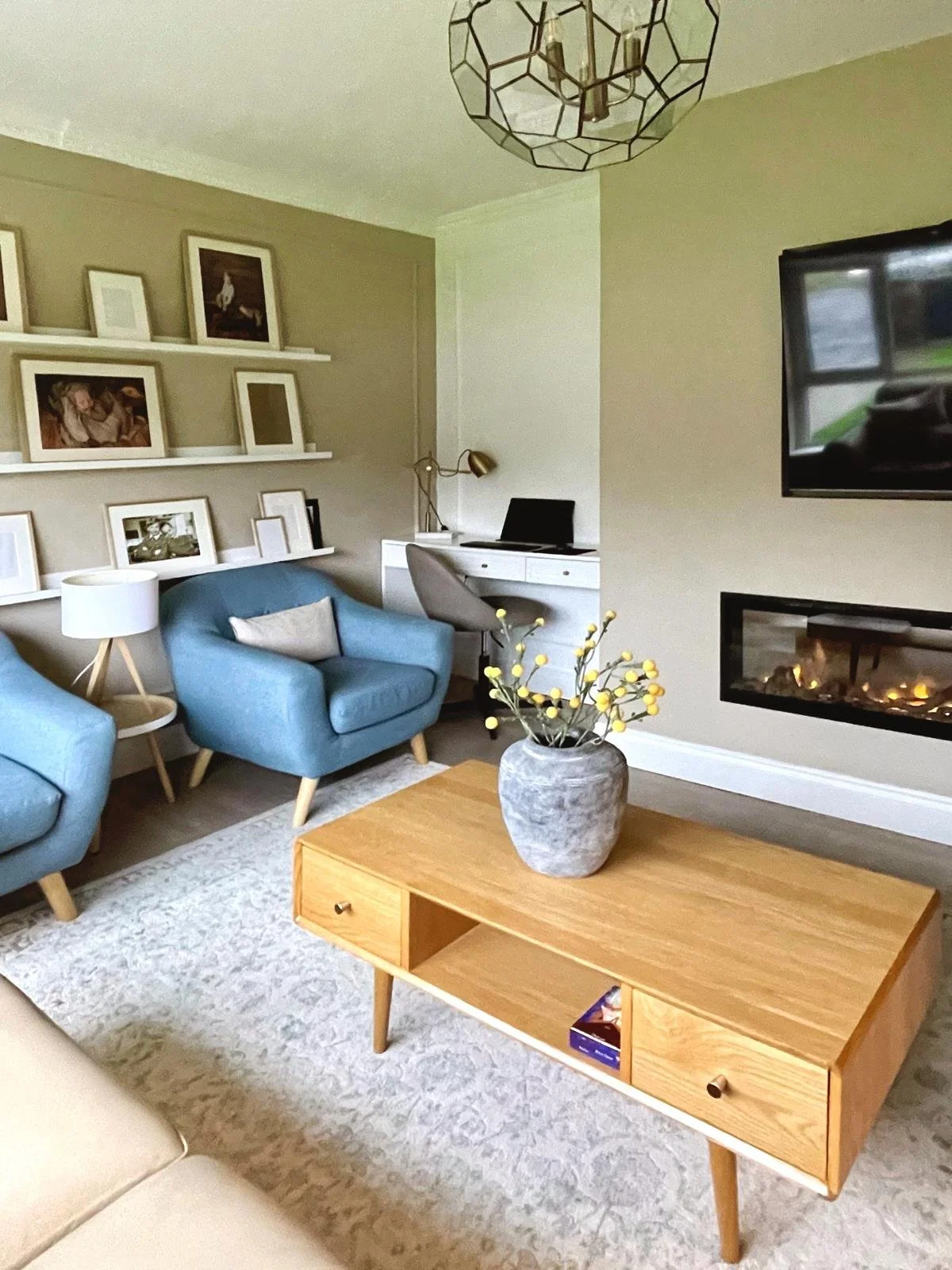 Living room with blue seating, open shelving, and a calm, comfortable layout centred around the fireplace.
