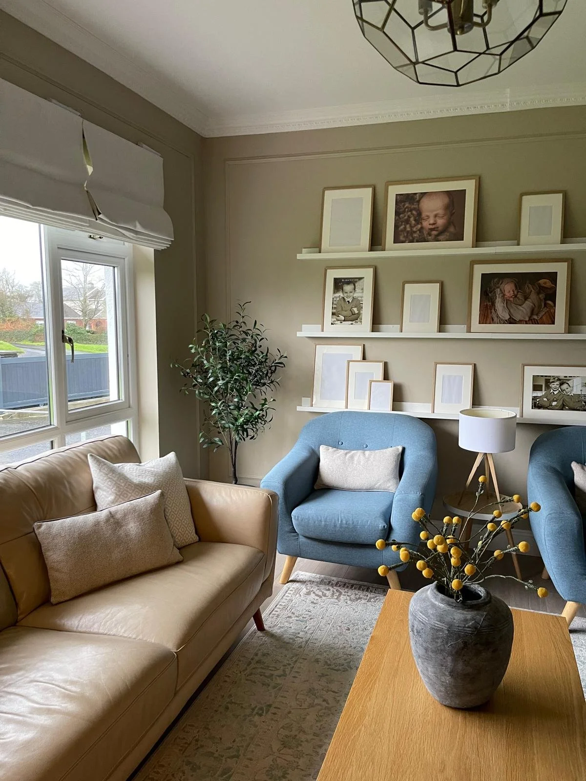 Living room with soft blue seating, open shelving, and a calm, comfortable layout centred around the fireplace.
