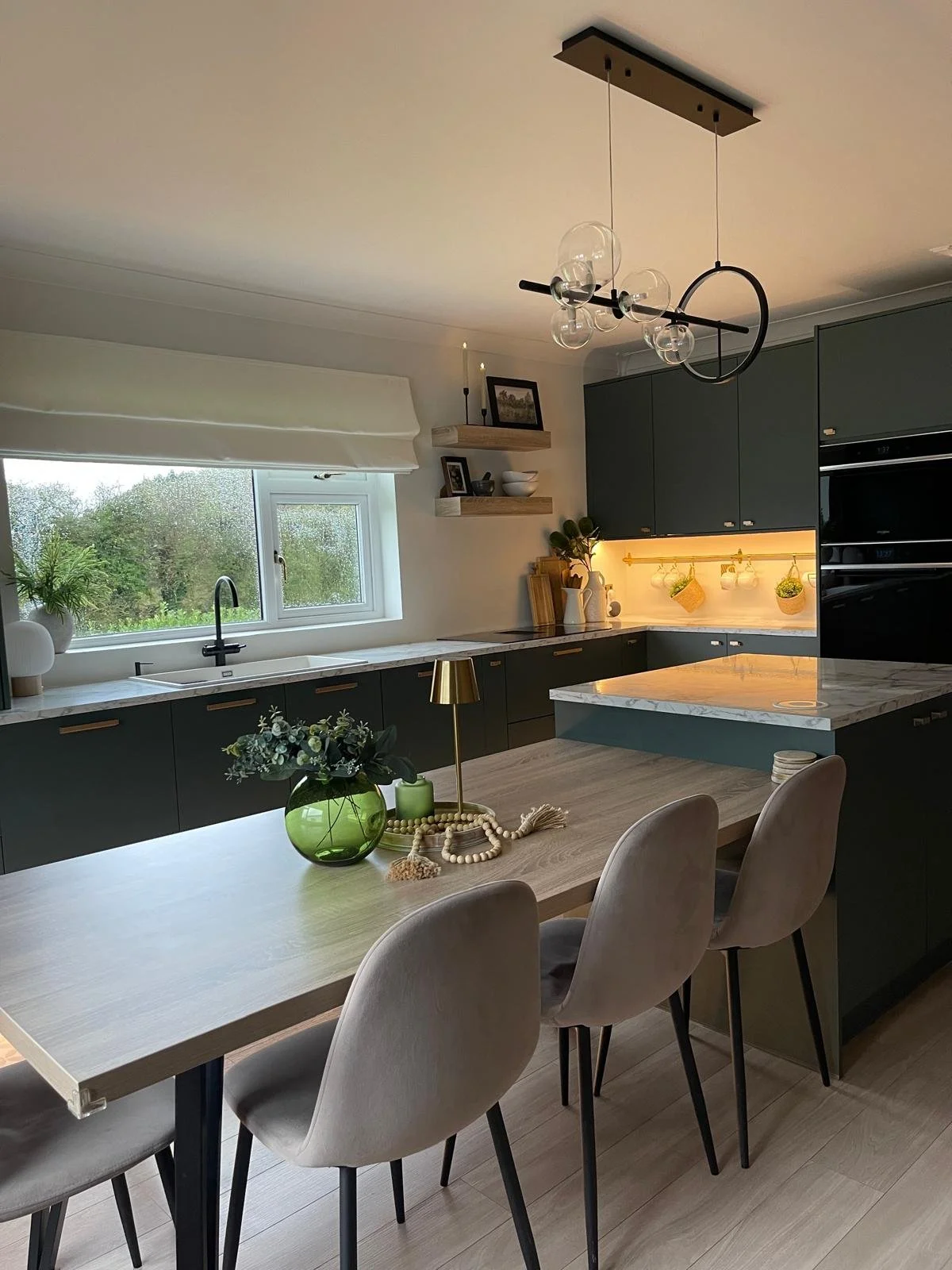 Kitchen and dining area with soft lighting, muted cabinetry, and a warm open-plan feel.