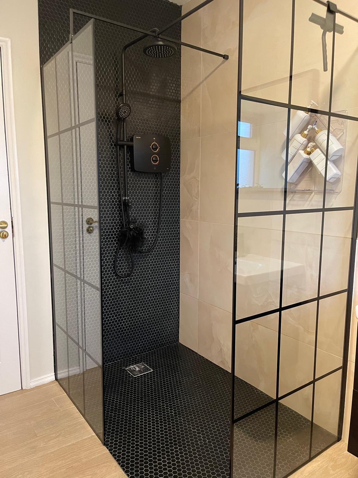 Bathroom detail with textured tilework, dark accents, and a more considered mix of finishes.