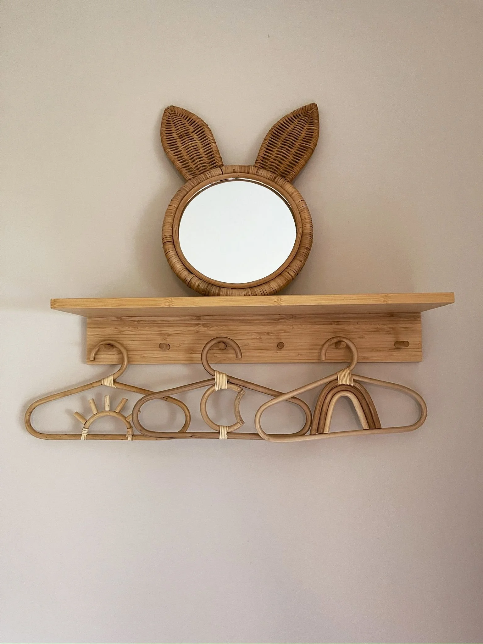 Decorative wall detail with a natural wood shelf, playful mirror, and charming handcrafted accents.