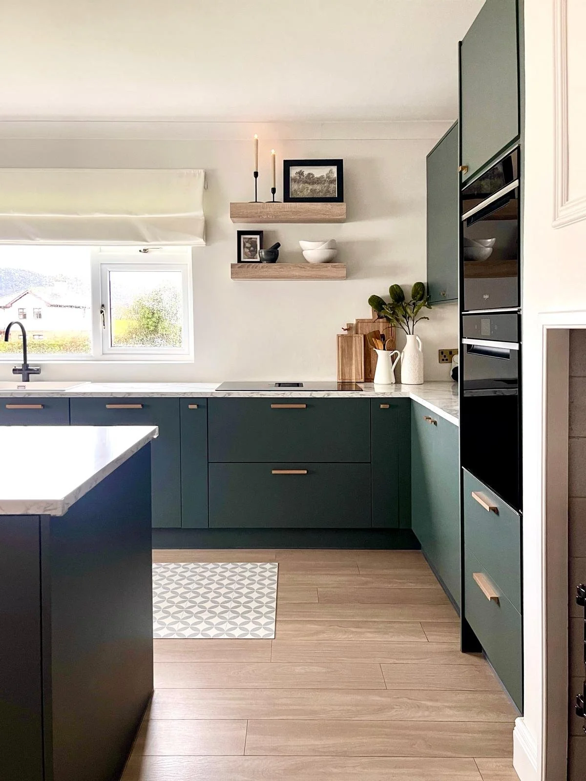 Kitchen styling detail with open shelving, marble-effect surfaces, and warm wood accents for a softly layered finish.