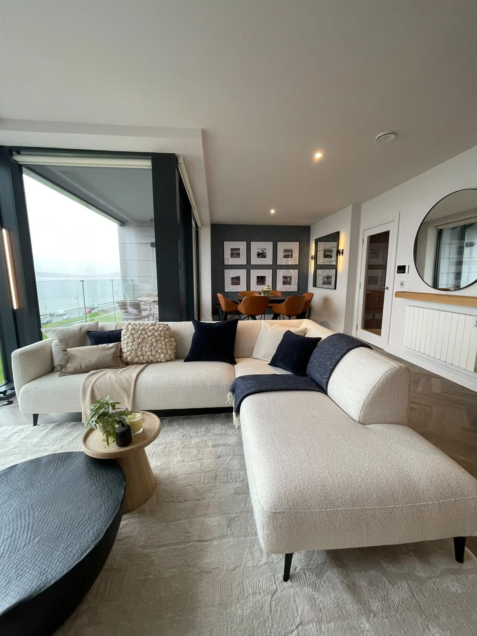 Modern living and dining room, Ireland. Navy wall, wallpaper, tan leather chairs