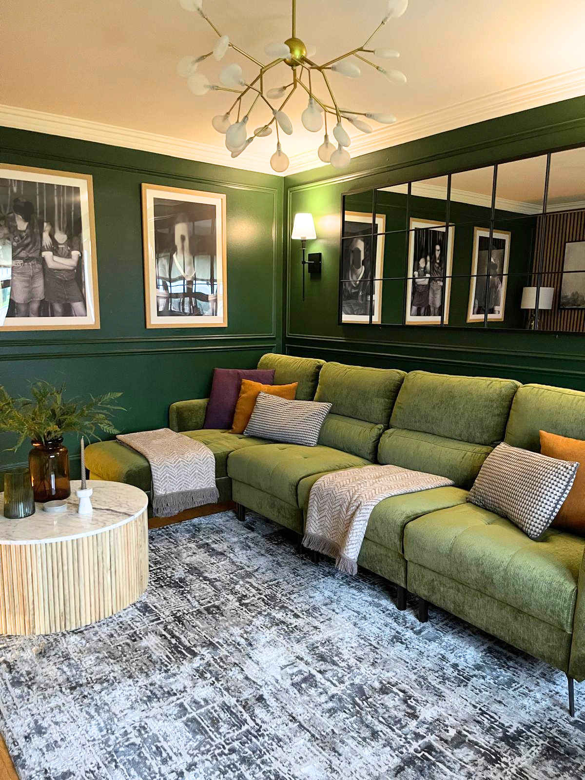 Finished living room with deep green walls, a large sectional sofa, framed artwork, and a warm, cocooning feel.