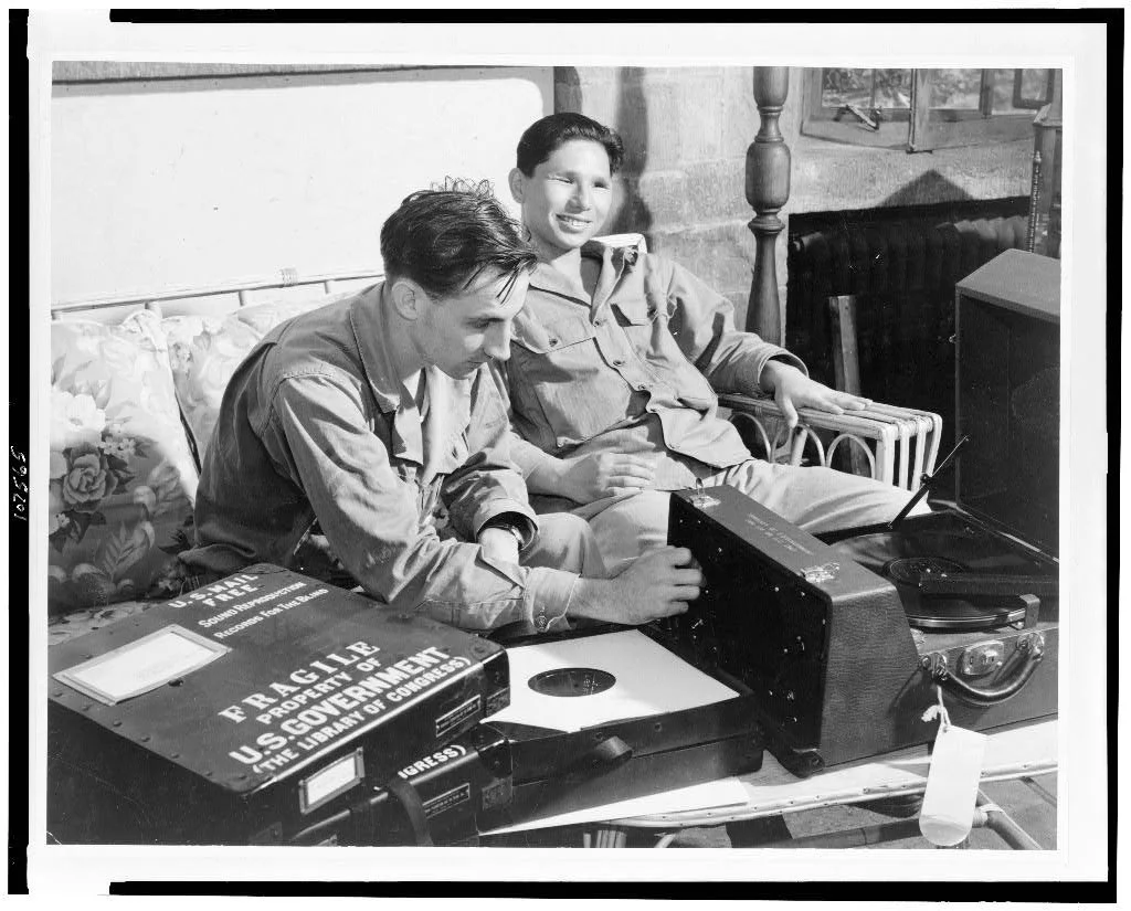 Two WWII-era airmen listening to a Library of Congress Talking Book record player.