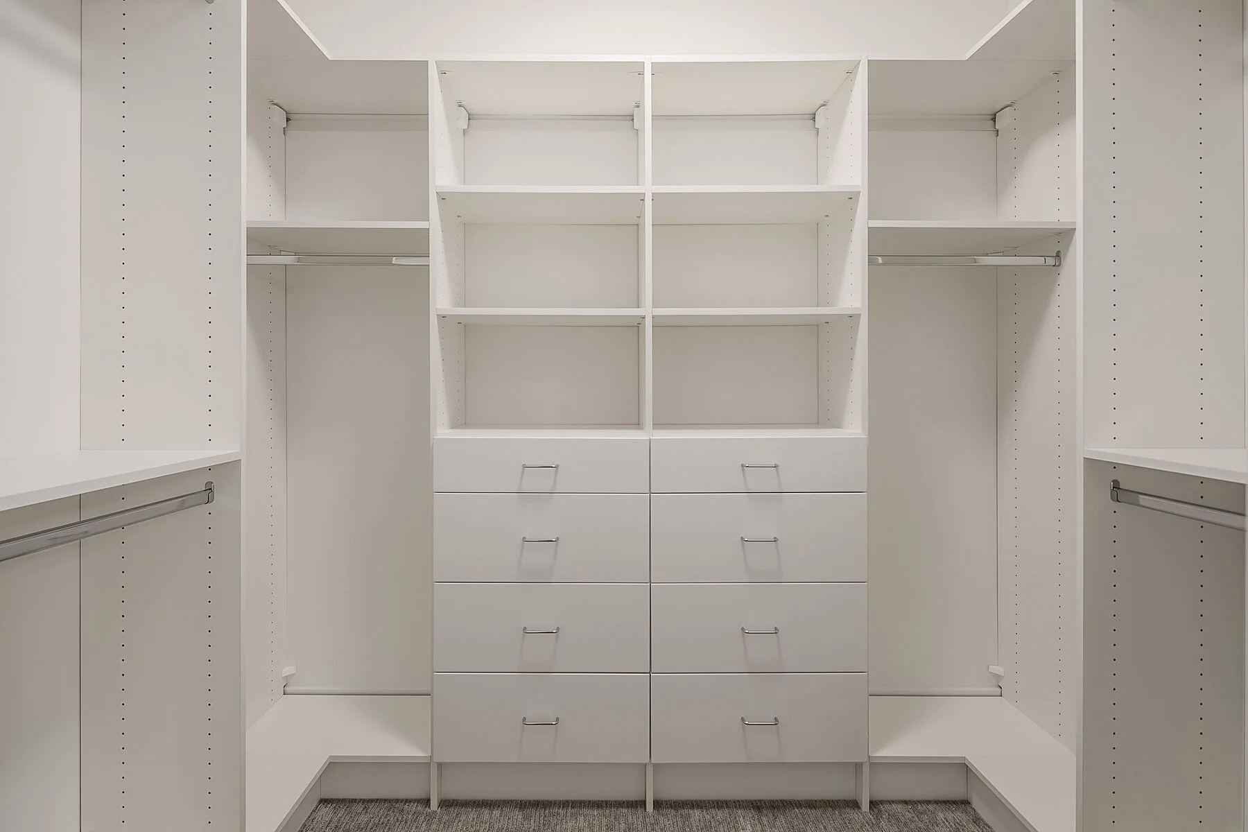 Empty white walk-in closet with shelves, drawers, and hanging rods.
