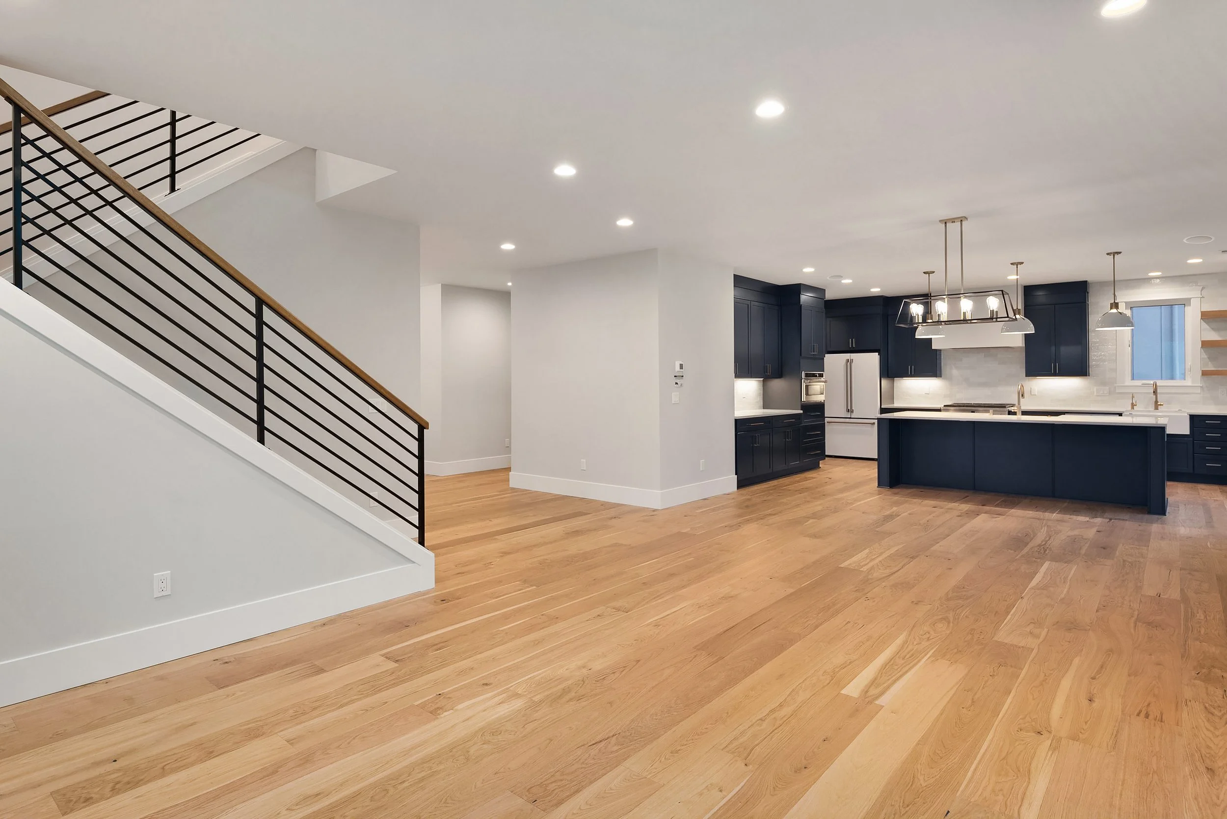 Open concept kitchen with dark blue cabinets, white marble countertops, and hardwood floors.