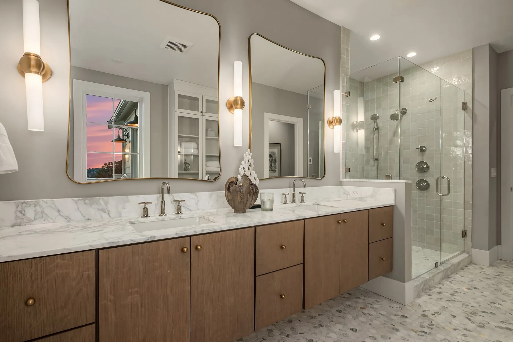 Modern bathroom with double vanity sinks, large mirrors, and a walk-in glass shower with multiple shower heads.