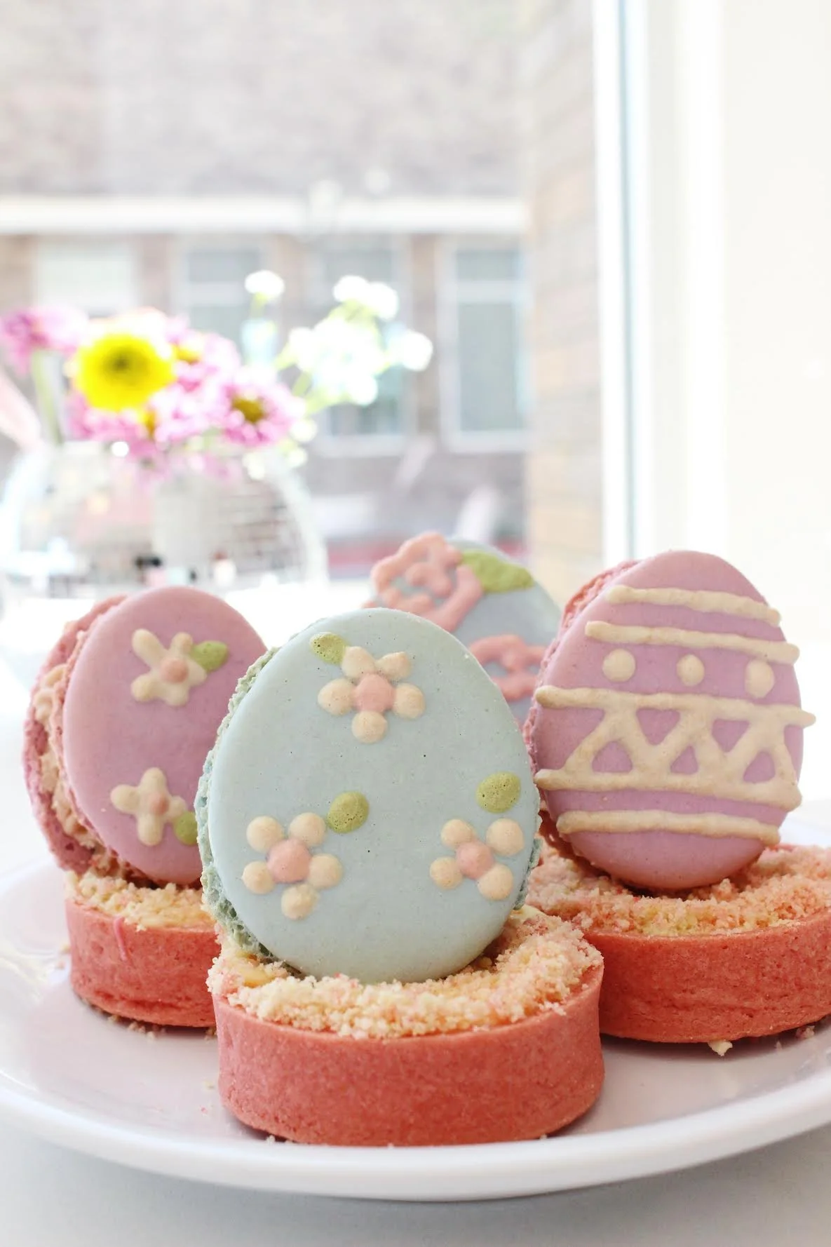 Easter-themed cookies decorated with pastel-colored icing and floral designs, arranged on a white plate — custom dessert catering and events by Decadent Macaron in Gilbert, Arizona