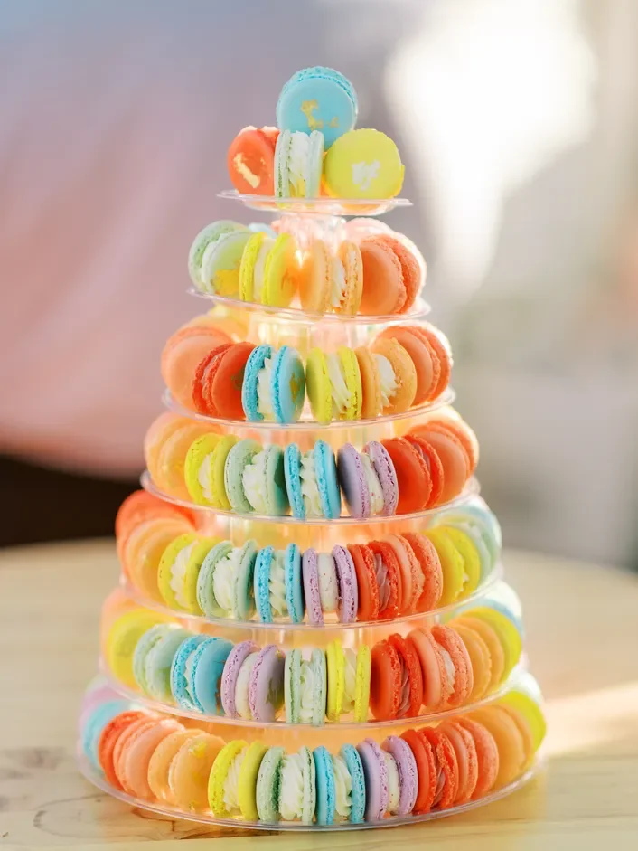 A multi-tiered display of colorful macarons arranged in a pyramid shape on a glass stand — custom dessert catering and events by Decadent Macaron in Gilbert, Arizona