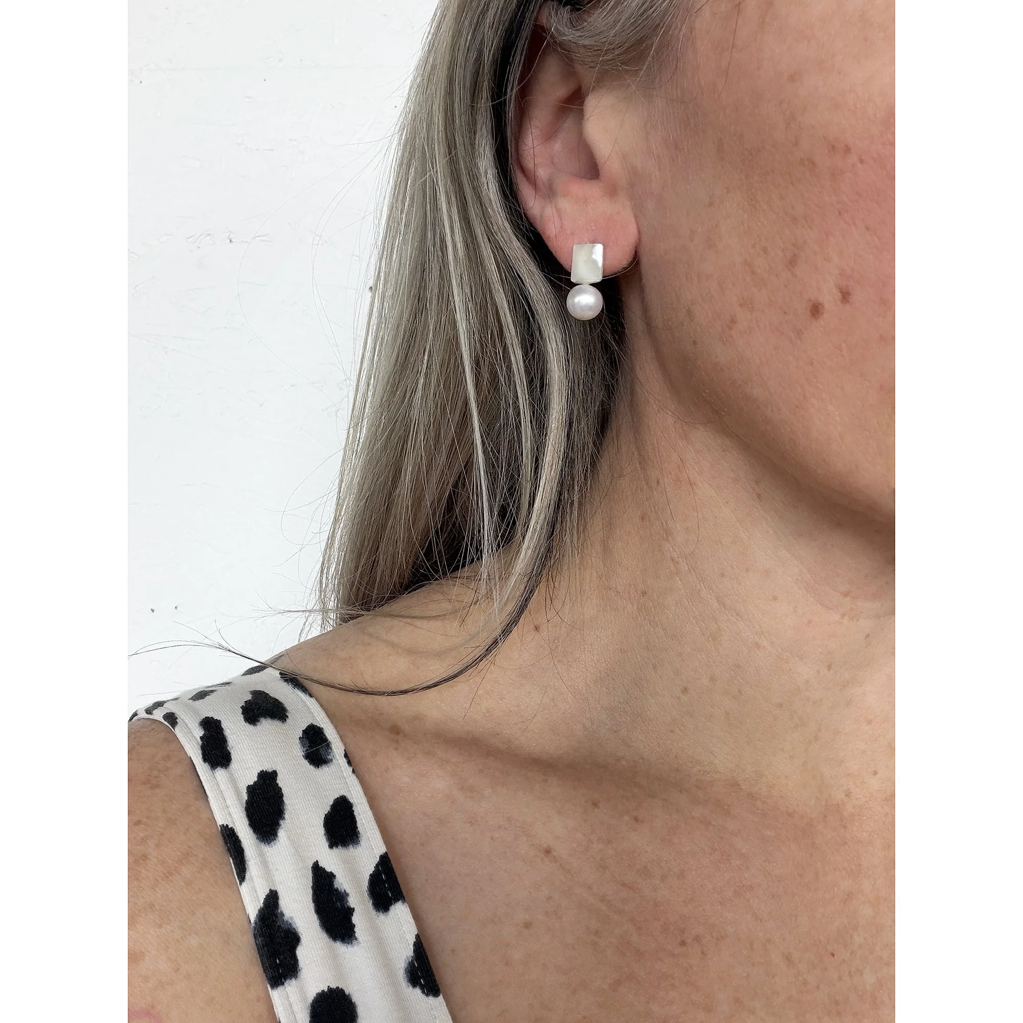 side view close up of woman with blonde hair and freckles wearing small pearl white round freshwater pearl and mother of pearl chunk earrings