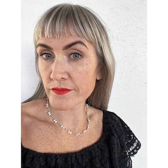 woman wearing scoop neck blue lace top and short white pearl necklace with black thread