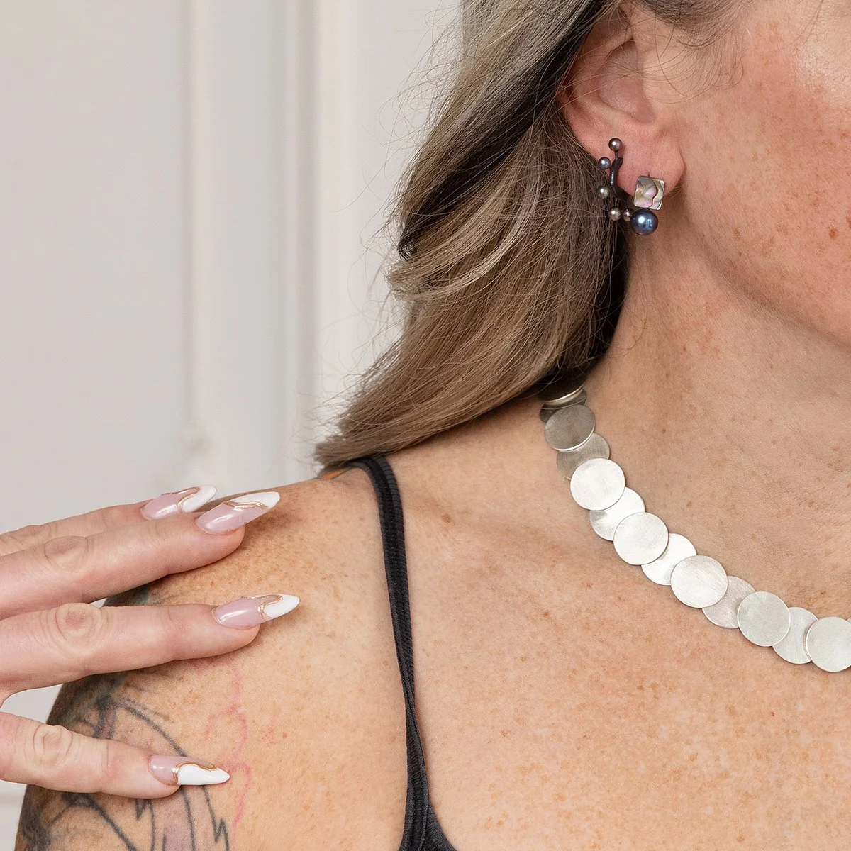 woman wearing small freshwater pearl earrings, small pearl hoop earrings and shiny sterling silver necklace