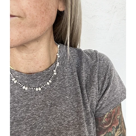 woman with gray tee shirt and blonde hair wear delicate small pearl necklace with black thread
