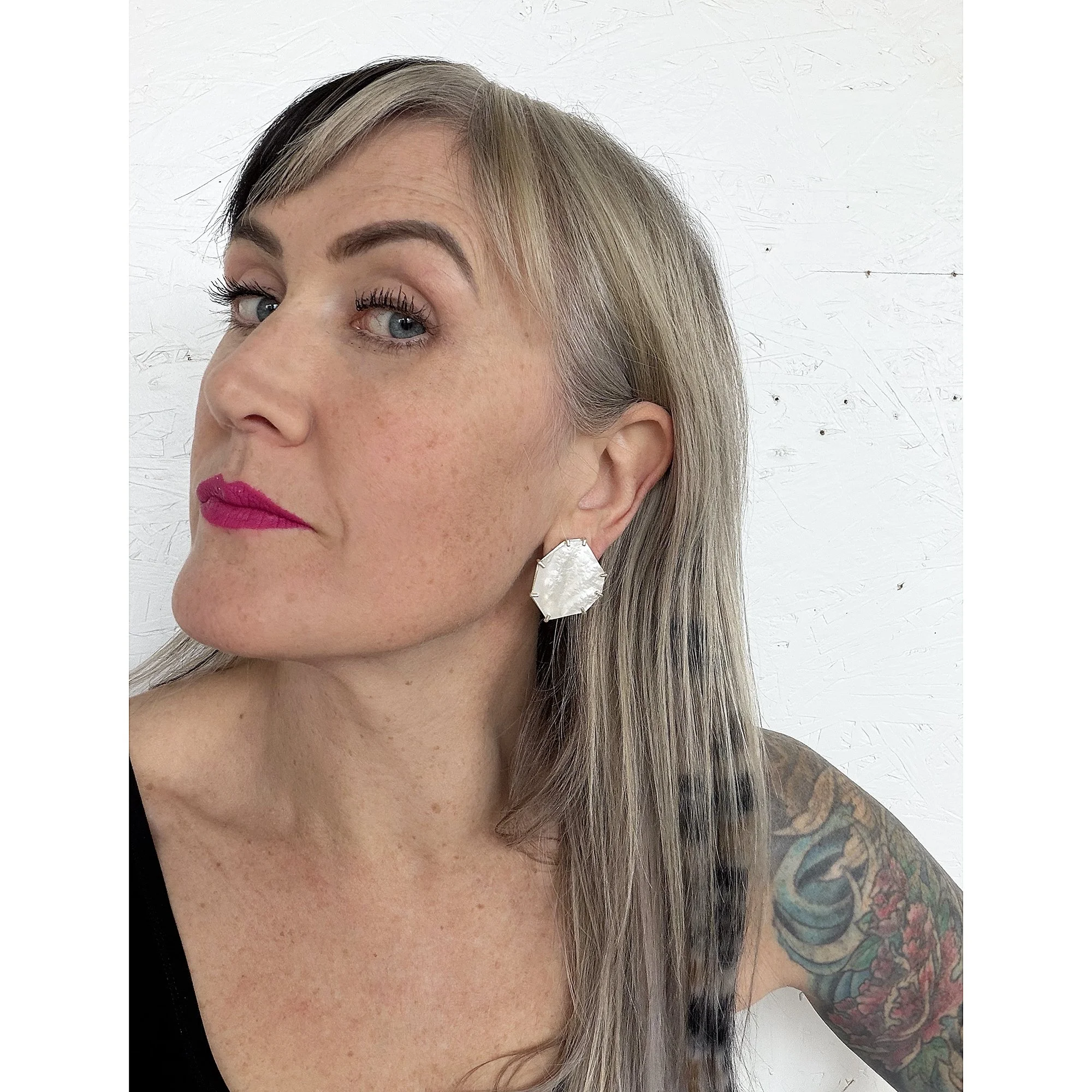 white gem like mother of pearl post earrings on woman with black tank top