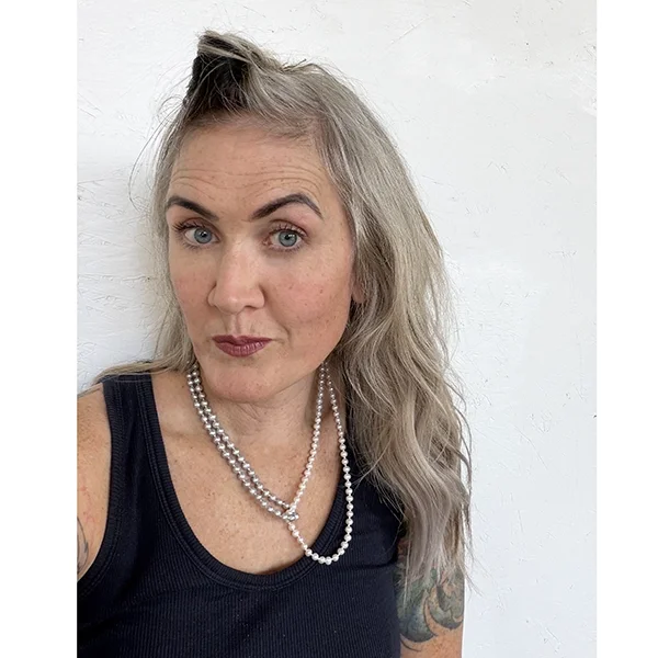 double strand silver and white freshwater pearl necklace on woman with blonde and black hair in front of white background