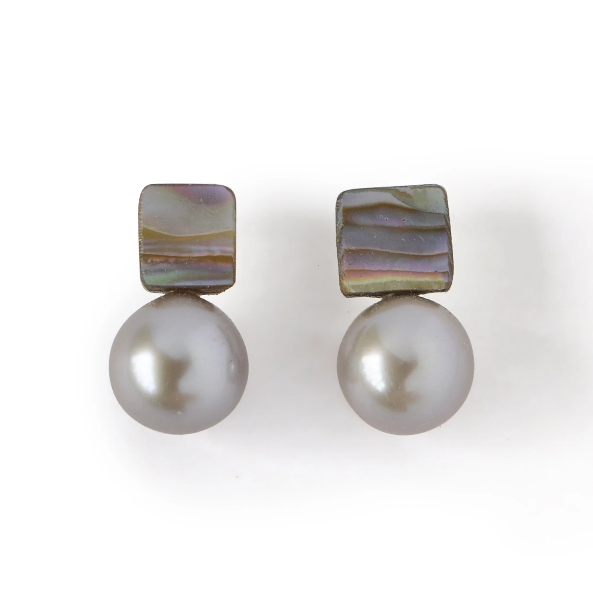 Small abalone shell earrings with waves of blue, green, pink and blue next to a big luscious silver freshwater pearl