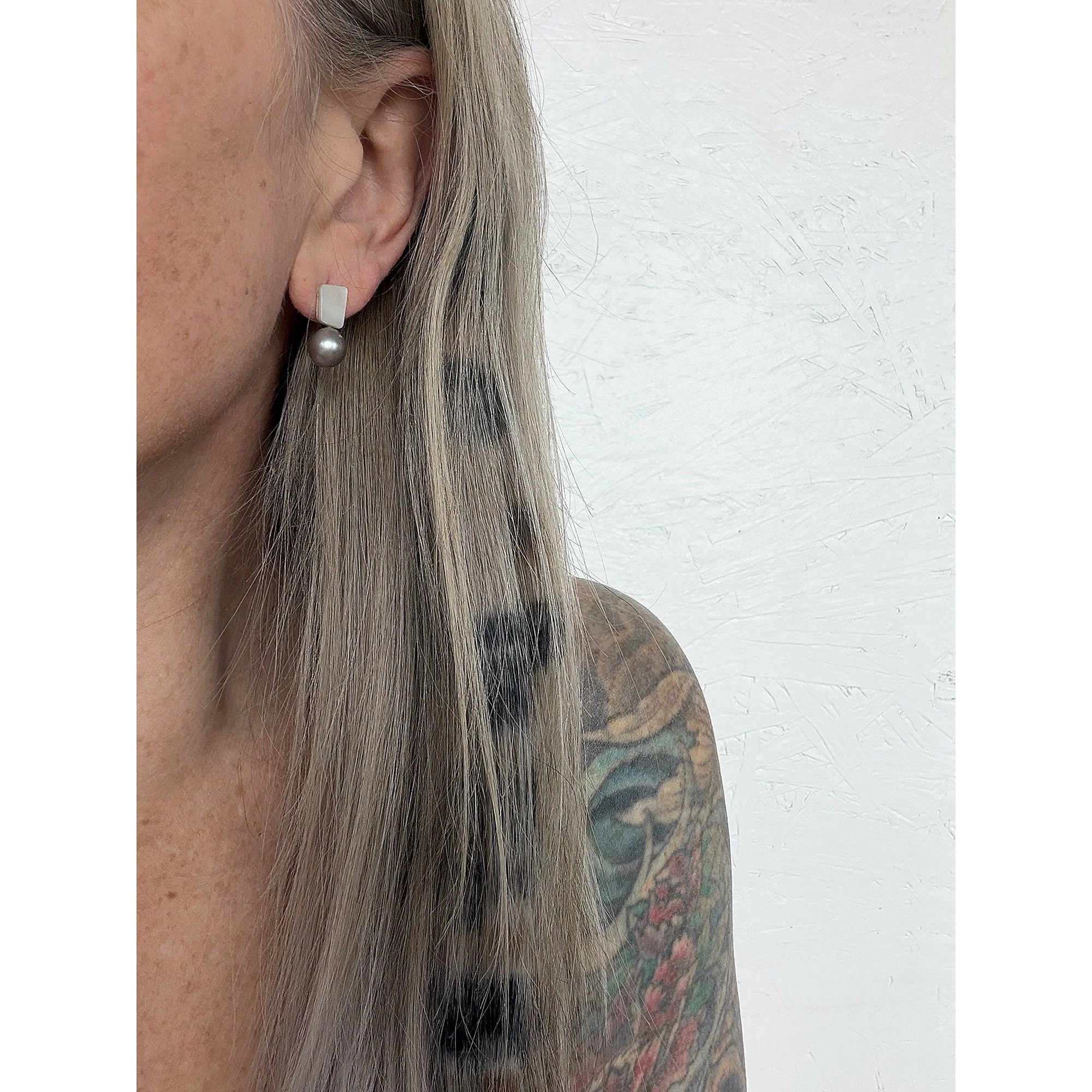 side view of woman with blonde hair and freckles wearing small silver pearl and mother of pearl earring