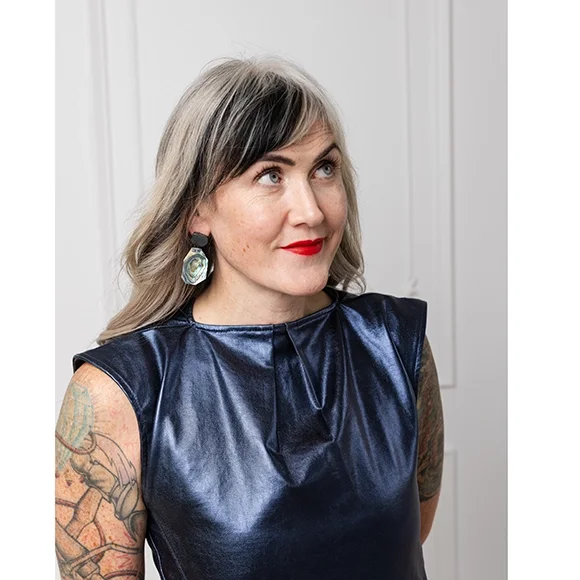 dark sterling silver and green irridescent earrings on woman with blue shimmery shirt red lips and wavy salt and pepper hair