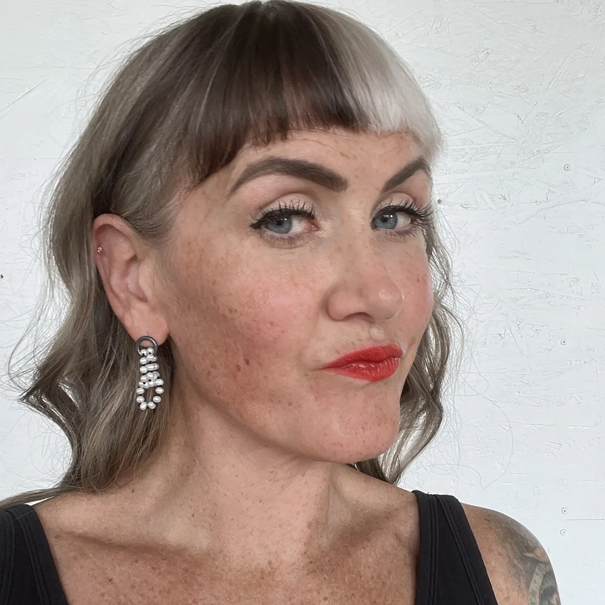 white pearl earrings with black sterling silver on woman with black and white wavy hair big eyelashes and red lips and black top in front of white backdrop
