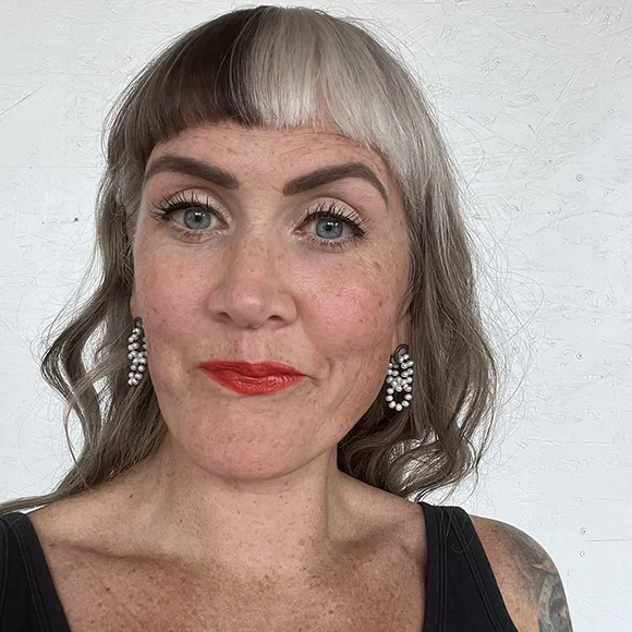 white pearl earrings with black sterling silver on woman with black and white wavy hair big eyelashes and red lips and black top in front of white backdrop